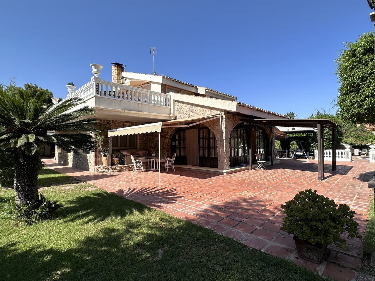 An elegant villa with multiple terraces, a spacious swimming pool, and a large, well-maintained garden. The property offers parking for several cars and the option to build a tennis court. The house features 5 bedrooms and 5 bathrooms, making it perfect for a large family or hosting guests. The ground floor includes three bedrooms, three bathrooms, a kitchen, and a bright living room with a cozy fireplace. On the upper floor, you’ll find the master bedroom with an en-suite bathroom featuring a hydromassage bath, along with a living room that opens onto a large terrace, perfect for outdoor relaxation. The basement is equipped with a bar, a billiard area, as well as an additional bedroom, living room, and bathroom. The house is equipped with solar panels, which significantly reduce electricity costs. Additionally, it features gas heating for optimal comfort. The villa is within walking distance of restaurants and just a short drive from a shopping center and the city of Elche.