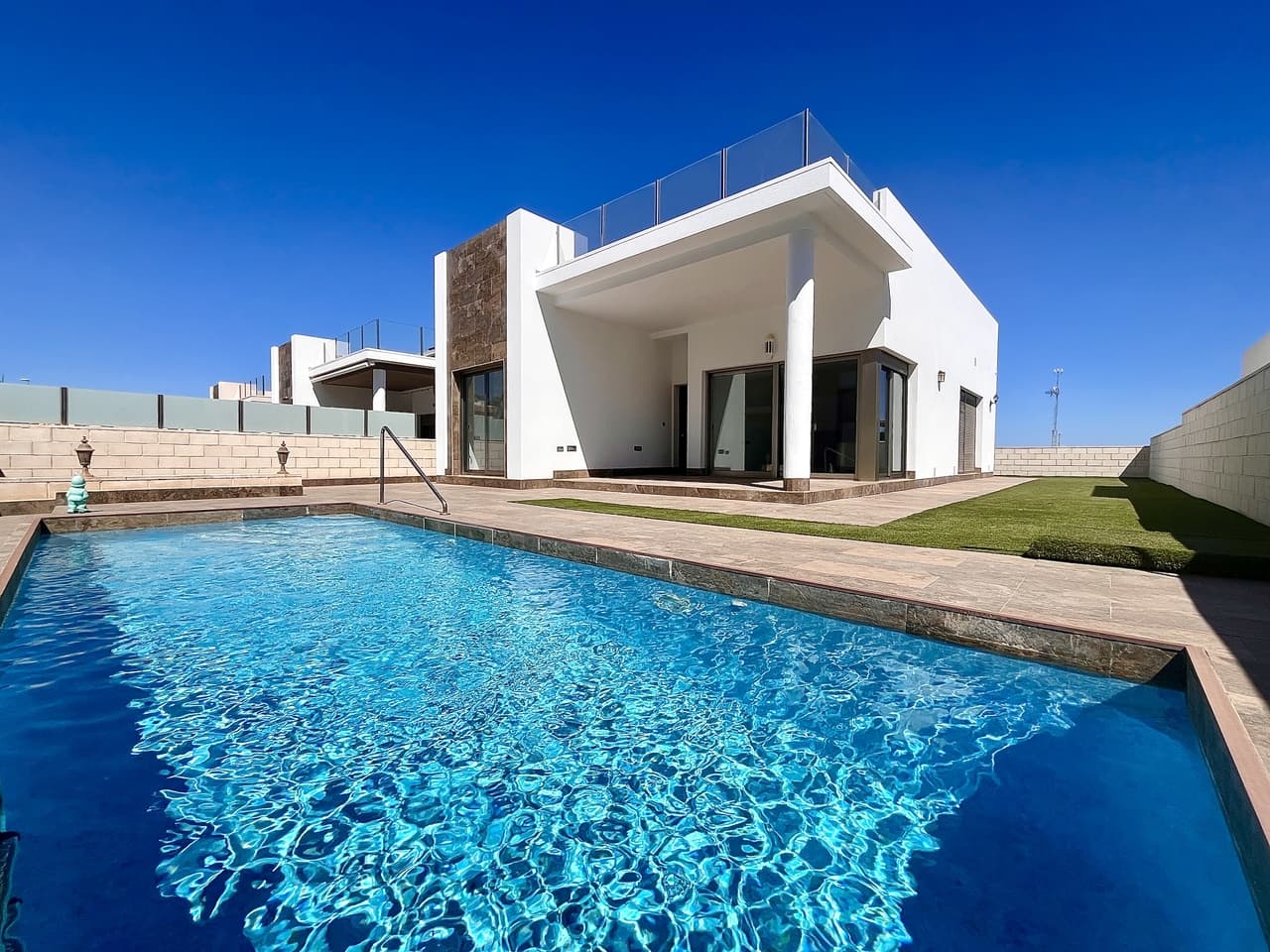 Super modern detached villa for sale located in an exclusive residential complex in Villamartin, just minutes from the well known Villamartin Plaza and the huge variety of international restaurants, supermarkets and convenience stores. This Villa has been built to a high standard and offers the perfect blend of comfort and luxury. This villa sits on a 330m South facing, sunny plot with private swimming pool, off road parking and wraparound sun terraces which have been finished with artificial grass for comfort. Inside is a huge living area with impressive floor to ceiling windows and patio doors providing lots of natural light and lead directly outside to a relaxing covered terrace area overlooking the swimming pool. There is an uber modern fully equipped kitchen with an independent utility, laundry and storage room. The villa has a huge master bedroom with en-suite bathroom, two double guest bedrooms and a family bathroom complete with bathtub. This villa also boasts a superb rooftop solarium with very pretty views towards the neighbourhood and out towards Torrevieja pink lakes. Built on one level this property provides ample space for holiday or full time living and has been finished with many many extras including electric blinds throughout and ducted air-conditioning. The villa has just been painted externally and is sold unfurnished.
