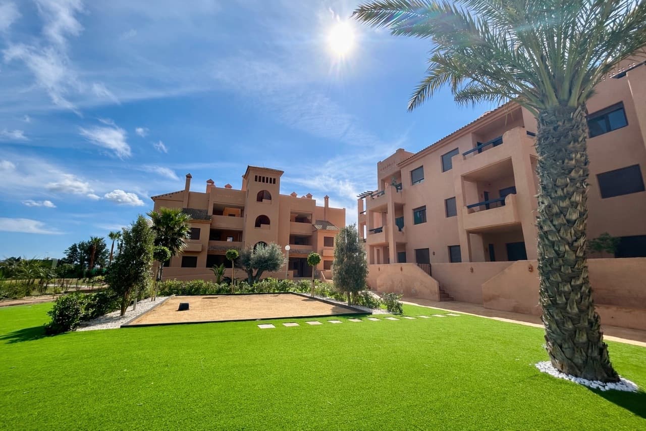 This stunning frontline ground-floor apartment is located in the prestigious La Serena Golf resort, offering breathtaking views across the golf course and the sparkling waters of the Mar Menor.Set within a beautifully maintained community, residents enjoy access to a communal swimming pool overlooking the golf course, creating the perfect setting to relax and take in the spectacular surroundings.The property boasts a large private terrace with golf and sea views, an ideal space for outdoor dining, entertaining, or simply enjoying the Mediterranean sunshine.As you enter the apartment, you are welcomed by a spacious entrance hallway that leads into the bright and modern living and dining area, designed to maximise natural light and the incredible views. The home also features a separate fully equipped kitchen, offering both practicality and generous storage space.The apartment offers three comfortable bedrooms, including a master bedroom with its own en-suite bathroom. The two additional bedrooms share a modern family bathroom, making the layout perfect for families or visiting guests. One of the guest bedrooms also provides direct access to a sunny rear terrace, adding another private outdoor space to enjoy.Additional features include two private parking spaces in the underground garage and two storage rooms, providing excellent convenience and extra space.Located just minutes from the beaches, restaurants, and marina of Los Alcázares, this exceptional apartment offers the perfect combination of luxury living, stunning views, and an unbeatable golf-front location.A fantastic opportunity for a permanent residence, holiday home, or investment property on the beautiful Costa Cálida.