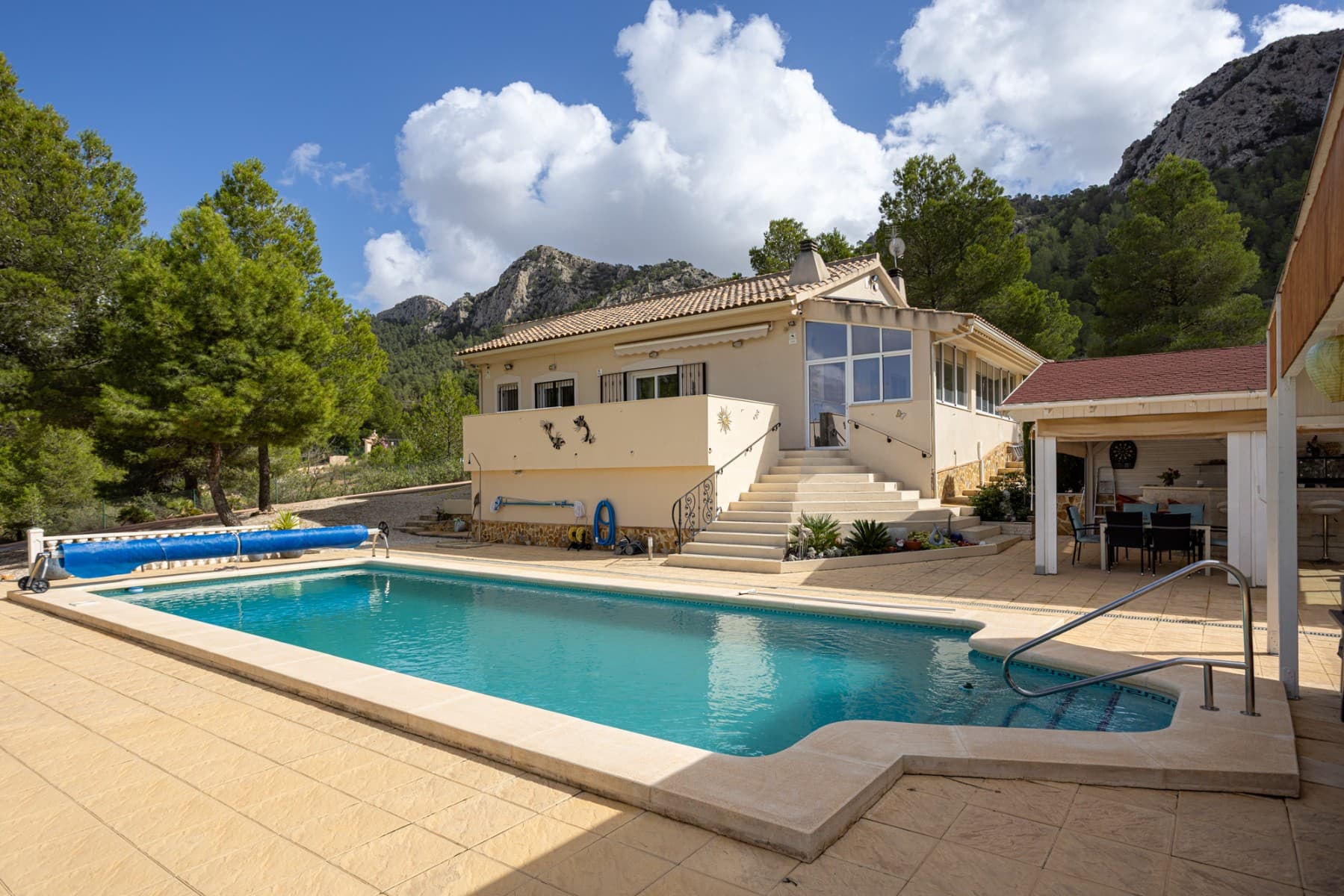 Discover this spectacular detached villa, nestled in the tranquil setting of La Zarza, where the mountainous landscape and rural surroundings are combined with all modern amenities. A unique property for those seeking privacy, space, and quality of life just an hour from the coast. The house has a built area of 134 m² and stands on an impressive 8,500 m² plot, with various outdoor spaces, mature gardens, and relaxation areas. Its southwest-facing location guarantees all-day sunshine and spectacular sunsets. Inside, the house boasts a cozy and functional design. It has four spacious bedrooms, all with abundant natural light, and two full bathrooms, ideal for both family use and entertaining. One bedroom is currently used as an office. The new open-plan kitchen integrates seamlessly with the living-dining room, creating a spacious and comfortable space for everyday use. The living room features a traditional fireplace, perfect for winter evenings, and the central heating ensures year-round comfort. The villa is fully furnished and equipped with appliances, ready to move into without renovation. It also has air conditioning for the warmer months. There are 15 solar panels for electricity and another 4 for water heating. The exterior is one of the property's greatest attractions: a beautiful private pool (heated for the winter months), a built-in barbecue with an outdoor kitchen and bar, a covered veranda for enjoying the outdoors even in the summer, and several terraces for relaxing or dining al fresco. There's also a private parking space and a storage room/wooden shed for additional storage. Underneath the terrace is a 30m² storage room. Prime location: Only 10 minutes from amenities, shops and restaurants 60 minutes from the Mediterranean beaches 60 minutes from the nearest international airport 40 minutes from golf courses Whether it is a permanent residence, a second home or an investment in rural tourism, this villa offers a perfect balance between tranquility, nature and comfort.