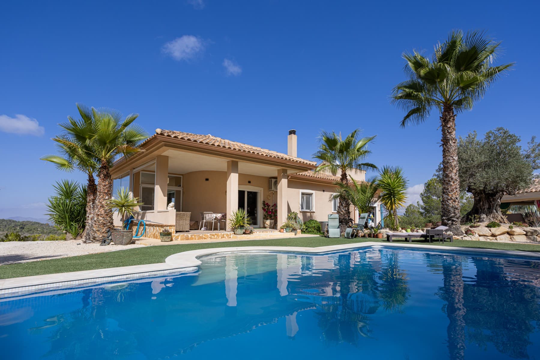 We present this beautiful detached villa, situated in a unique natural setting in La Zarza, where the tranquility of the countryside is combined with all modern amenities. Ideal as a permanent residence, holiday home, or even as a rural investment.

 Layout and interior spaces

 With a built area of 144 m², this charming home offers a functional and bright layout. The house features three spacious bedrooms (one of which has been converted into a garage, but is easily converted), all with abundant natural light, and two carefully finished bathrooms, as well as a guest toilet for added convenience.

 The open-plan kitchen, fully equipped with appliances, flows seamlessly into the living-dining room, creating an open and welcoming space, ideal for enjoying with family or friends. The living room features a cozy wood-burning stove, perfect for winter evenings. The house also has central heating (propane) and air conditioning for optimal comfort year-round. One of the most special features of this property is the underfloor heating throughout the house and the use of a unique water system connected to the gas central heating system.

 The house is fully furnished and equipped, move-in ready, and features built-in wardrobes for extra storage. The master bedroom boasts a fantastic walk-in closet and an en-suite bathroom. A real eye-catcher in this bathroom is the jacuzzi with shower. The walk-in closet can even be converted into an additional small bedroom if desired.

 The house has 18 solar panels for the house and another 6 solar panels for the boiler.

 Exterior: Nature, privacy and outdoor recreation

 The true luxury of this property lies outdoors. Situated on an impressive 13,400 m² plot, surrounded by nature, it offers complete privacy and spectacular open views of the landscape.

 The meticulously maintained garden leads to a fantastic private swimming pool, ideal for cooling off in the summer, but also heated for cooler winter days. It also features a barbecue area, a covered veranda perfect for al fresco dining, a large sun terrace, and a solarium for enjoying unforgettable sunsets.

 There is also a closed garage and a private parking space on the plot.

 Location and accessibility

 Although the villa offers complete tranquility, it is very easily accessible:

 Recreation areas, restaurants and amenities are just a 10-minute drive away. Prestigious golf courses are 40 minutes away. Both the Mediterranean beaches and the nearest airports are 60 minutes away, making it an excellent choice for frequent day trips or international visits.

 The south-westerly location guarantees sunshine and spectacular natural light for most of the day.

 Included extras Air conditioning Electric roller shutters (persianas) throughout the house Central heating (propane gas, 1000 liter tank) Water tank (21,000 liters) Fireplace (for wood) Solar panels (for electric heating and hot water) Furnished Appliances (main kitchen appliances) Barbecue and outdoor seating area All automatic gates are operated with GSM WiFi Private swimming pool (heated by solar boiler) Garage and parking space Veranda, terrace and solarium Large private garden