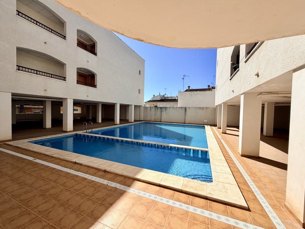 Discover this beautiful and spacious 140 m² apartment located in the charming town of San Fulgencio, perfectly situated within walking distance of all essential services, shops, restaurants, and local amenities. This property offers the perfect balance between a peaceful residential environment and convenient access to everything you need for everyday living. In addition, the stunning beaches of La Marina are only a 15-minute drive away, allowing you to enjoy the Mediterranean lifestyle whenever you wish.The apartment is very well maintained and ready to move into, making it an excellent option both as a permanent residence or as a holiday home on the Costa Blanca. As you enter the property, you will find a large and bright living room that provides a comfortable and welcoming space for relaxing or entertaining guests. The lounge benefits from air conditioning and a ceiling fan, ensuring a pleasant temperature all year round.The property offers three spacious bedrooms, all equipped with air conditioning for maximum comfort. The master bedroom features its own en-suite bathroom, providing privacy and convenience. In total, the apartment includes two bathrooms, both in excellent condition and ready for immediate use.The semi-independent kitchen is another highlight of the home. It is in very good condition and offers plenty of space, large enough to comfortably accommodate a table and chairs. There is also ample room for a double refrigerator and additional storage, making it a very practical and functional cooking area.One of the most enjoyable areas of the property is the covered terrace, an ideal space to relax at any time of the day. From here you can enjoy pleasant mountain views while having breakfast, lunch, or dinner, making it a perfect place to unwind and enjoy the peaceful surroundings.The building itself offers several convenient features, including an elevator for easy access, a communal swimming pool where residents can cool off during the warm summer months, and a shared solarium ideal for sunbathing and enjoying the Mediterranean climate.Additionally, the apartment includes a private underground storage room, providing valuable extra space for storing bicycles, seasonal items, or personal belongings.The property is sold unfurnished, giving the new owners the opportunity to decorate and furnish the home according to their own taste and style. All essential elements of the property are already in excellent condition, meaning you can move in and start enjoying the home right away.San Fulgencio is one of the most well-developed and sought-after areas in the region, known for its quiet atmosphere while still being close to all services. The town hall, schools, shops, and other amenities are just a short walk away, making everyday life easy and convenient.This apartment truly offers space, comfort, and an excellent location close to the coast. Contact us today to arrange a viewing and discover this beautiful property for yourself.
