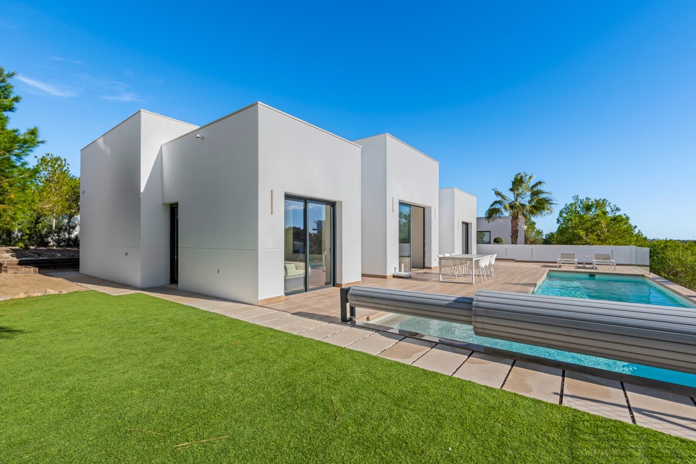 Located in the prestigious Las Colinas Golf & Country Club, one of the most exclusive resorts on the Costa Blanca, this breathtaking villa offers the perfect blend of modern design, high-end finishes, and ultimate living comfort. Designed to maximize enjoyment of the sun and nature, the villa features a southeast orientation and expansive windows that provide panoramic views of the lush surroundings.

Upon entering, you are welcomed into a spacious and bright living area, where elegance and functionality blend seamlessly. The open kitchen, equipped with high-quality built-in appliances, flows effortlessly into the stylish living room—a perfect space to unwind in luxury or entertain guests in a sophisticated setting.

Villa Layout

The villa boasts an impressive master suite on the ground floor, complete with a spacious walk-in dressing room and a luxurious en-suite bathroom. Additionally, this level features two extra bedrooms, sharing a modern bathroom. Each of these rooms offers peace and privacy, with direct access to the outdoor spaces and stunning natural views.

In the lower level, you will find an exclusive studio, ideal as a guest retreat or for added privacy. The studio includes a spacious bedroom, a stylish bathroom, and a private wellness area—a sanctuary where you can fully relax and recharge.

Outdoor Living & Technology

The southeast-facing garden is designed for ultimate outdoor enjoyment. The heated private pool invites you for a refreshing swim any time of the year, while the expansive terraces provide the perfect setting for long summer evenings.

This villa is equipped with the latest modern technologies, including a smart home automation system, allowing you to easily control lighting, climate, and security. The Airzone climate control system ensures perfect indoor comfort in every room, while the automatic shutters provide extra convenience and privacy. Additionally, solar panels make this home more energy-efficient and sustainable.

For your convenience, the villa offers a private parking area for two cars, ensuring a safe and comfortable space for your vehicles. Moreover, the property is fully furnished, including luxurious furniture worth €30,000—every detail is meticulously finished and ready for immediate move-in.

Living in Las Colinas Golf & Country Club means enjoying a top-tier lifestyle. In addition to its award-winning golf course, the resort offers various sports facilities, fine dining restaurants, and a serene, secure environment. Furthermore, the stunning sandy beaches of the Costa Blanca are just a short drive away, allowing you to experience the best of both worlds—tranquility and exclusivity, with the Mediterranean Sea within easy reach.

Are you looking for a luxurious villa with space, privacy, and an exceptional location? Contact us today to schedule a viewing and experience this unique living opportunity for yourself!