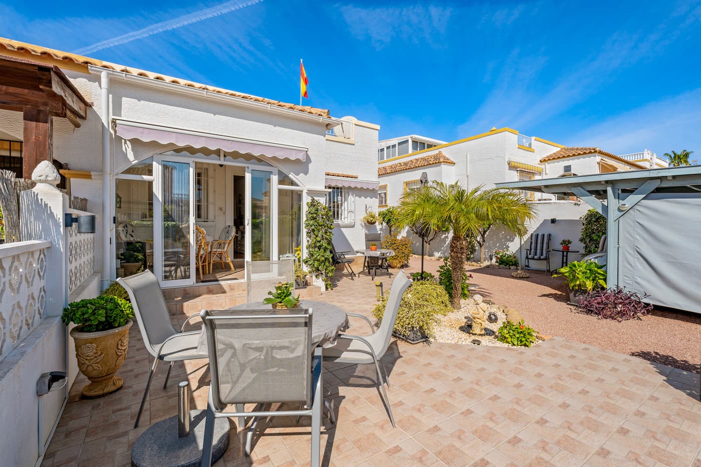 This charming and well-maintained quad house from 2003 is located in the popular area of La Marina and is ready to move into.The property is sold furnished, so you can move straight in and start enjoying life under the Spanish sun.At the entrance to the house, you will find a lovely covered terrace that has been enclosed with glass. This provides an additional living space where you can sit sheltered and enjoy your morning coffee – even during the cooler months.Inside, you are welcomed into a bright and inviting living room with an open-plan connection to the kitchen. There is plenty of space for both a sofa area and a dining table, making this room a natural gathering point for everyday life and guests alike.From the living room, a hallway leads to the property’s three bedrooms and the bathroom – all equipped with wardrobes.The bathroom is located at the end of the hallway and features a shower cabin.From the kitchen, there is access to the back of the house, where a practical covered area has been created. Here you will find a functional utility room with both a washing machine and dryer, as well as good storage space. From this area, stairs lead up to the property’s beautiful rooftop terrace.The covered area continues over the first part of the rooftop terrace, creating an additional living space that can be used as a conservatory, lounge area, or shaded seating area. The Glazed terrace is especially practical during the winter months.The rooftop terrace itself remains spacious, offering plenty of opportunities to enjoy the sun all day. It is perfect for cozy barbecue evenings and relaxing moments under the stars on the many warm Spanish nights.The plot surrounding the house is very charming and well-designed, featuring fruit trees, small green oases, and several lovely seating areas where you can enjoy the sun throughout the day. There is also a carport on the plot and a practical storage shed.The property has been well cared for and is in very good condition.Air conditioning is installed in the living room and in one of the bedrooms.The property also includes access to a lovely communal pool area with both a large pool with a children’s pool. The area is landscaped with real grass, creating a cozy and green atmosphere. There are both parasols and pergolas, making it easy to find shade on hot summer days. It is a wonderful place to spend sunny days – whether you want to take a refreshing dip, relax with a good book, or simply enjoy a day by the pool.The house is located in a quiet and well-established area of La Marina. Restaurants and cafés are within walking distance, while several supermarkets and shopping facilities are under 2 km away.The beautiful sandy beaches of La Marina and Guardamar can be reached in just a few minutes by car – only about 3.5 km away. The area is also known for its cozy atmosphere, great restaurants, and stunning natural surroundings with pine forests and dunes along the coastline.Alicante Airport is approximately 30 km away via the N332, which is easy to access.A wonderful home with great outdoor areas and plenty of possibilities – perfect as a holiday home or for longer stays in Spain.
