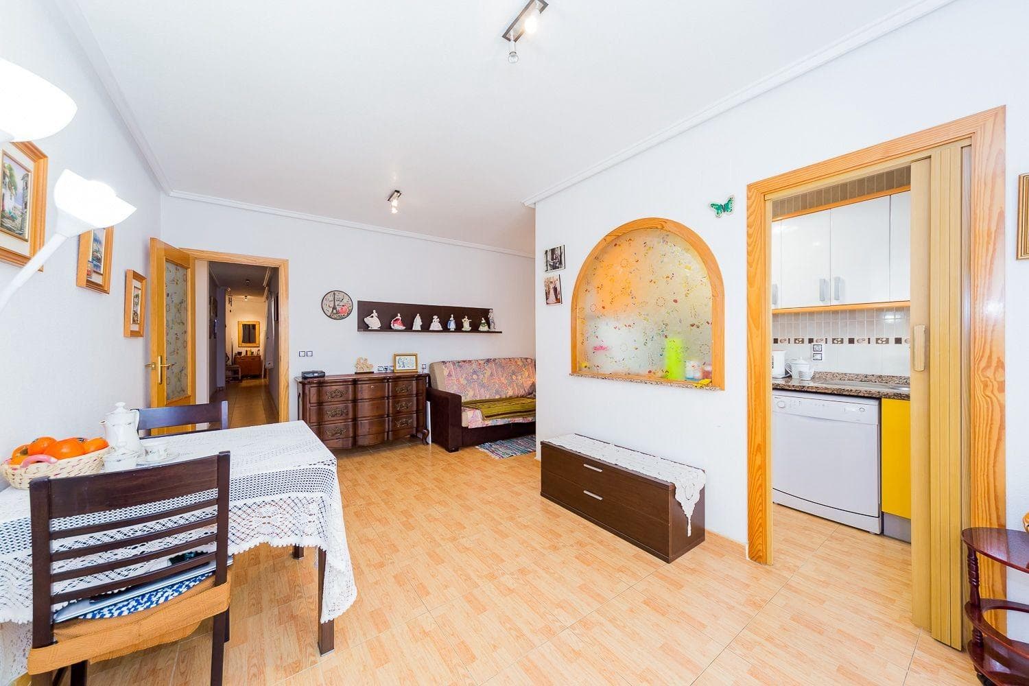 Leilighet til salgs: romslig stue med balkong og åpen kjøkkenløsning, to separate soverom med innebygde garderober og et komplett bad. Total areal på leiligheten: 86 m², boareal: 76 m². Leiligheten ligger i det rolige sentrum av Torrevieja, i 3. etasje i en 5-etasjers bygning fra 2008, nær Parque de las Naciones, i San Luis gate 4. Sandstranden Acequión ligger 400 meter unna i luftlinje. Alt er i nærheten: skole, park, busser, butikker og kafeer. Selges fullt møblert, med hvitevarer og klimaanlegg.