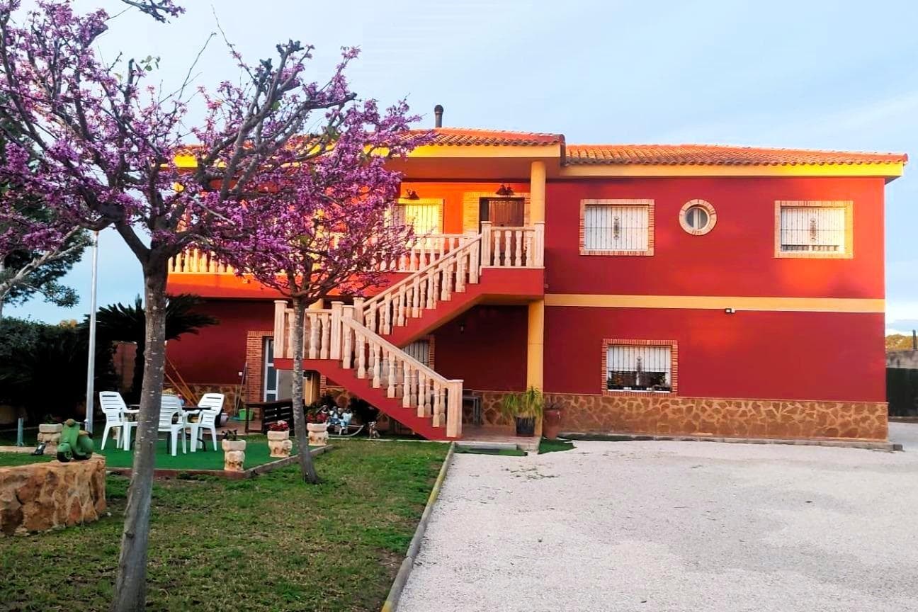 MAGNÍFICA VILLA (253 m² – 1200 m² DE PARCELA) CON 5 DORMITORIOS, 3 BAÑOS, DOS COCINAS, AMPLIOS SALONES Y GARAJE. CONSTRUIDA EN 2010 CON LAS MEJORES CALIDADES. A APROX. 3 KM DEL CENTRO DE ORIHUELA Y RODEADA DE HUERTOS. Rodeada de huertos y con vistas a las montañas, se encuentra esta magnífica villa, construida en 2010, con 5 dormitorios, 3 baños y amplios salones. La casa está amueblada con dos cocinas completas y puede utilizarse como dos viviendas independientes. En la amplia parcela, con amplio espacio para construir una gran piscina, también hay un amplio trastero independiente (aprox. 40 m²). Ideal para quienes buscan un lugar tranquilo para vivir fuera de la ciudad, para una convivencia multigeneracional o para gestionar un negocio que necesita espacio. CARACTERÍSTICAS PRINCIPALES: –Entorno tranquilo con huertos y vistas a la montaña. –Planta alta: Amplio salón con chimenea, sala de estar con mesa de billar, amplia cocina independiente con comedor, 3 dormitorios, 2 baños y una gran terraza con maravillosas vistas. –Planta baja: Salón con comedor y cocina abierta, 2 dormitorios, 1 baño, lavadero, trasteros, amplio garaje y terraza frente a la entrada. –Parcela de 1200 m² - amplio espacio para construir una gran piscina. OTRAS VENTAJAS: –Trastero independiente (aprox. 40 m²). –Varios equipos de aire acondicionado modernos (bombas de frio/calor). –Paneles solares en el tejado del trastero. –Ubicación estratégica cerca de la A7, a solo 20 km de Murcia y 30 km de Torrevieja. La casa fue construida en 2010 con una alta calidad constante, tanto en construcción como en materiales. Se encuentra en muy buen estado, ¡lista para entrar a vivir! En coche se puede llegar a Murcia y Torreveja en 30 minutos, y situado a sólo 500 m de la Universidad Miguel Hernández en Desamparados, también hay transporte público en funcionamiento, a pesar de la ubicación rural. ¡No se pierda esta magnífica villa, perfecta para una familia numerosa, para vivir con varias generaciones o para quienes también necesitan espacio para un negocio! Contáctenos hoy mismo para reservar una visita. ¡Escríbanos y le pondremos en contacto con un miembro del equipo que habla su idioma!