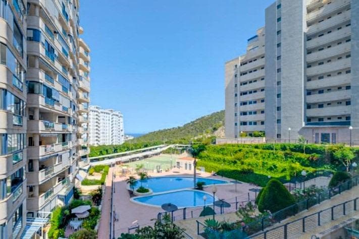 COZY APARTMENT (66 m2 - floor 10) WITH 1 BEDROOM, LARGE TERRACE, LARGE COMMUNITY POOL, AND ONLY 600 M TO THE BEACH! Apartment on the 10th floor in the popular Residencial Las Azaleas with a large pool area and only 600 m from the beach Playa de la Cala de Finestrat. Quiet area with many cozy restaurants and cafes nearby and very good public transportation both to Benidorm (a few km north) and to the large shopping centre La Marina with Carrefour and many other shops. Just as perfect to live in all year round as a holiday apartment, both for yourself or as an investment for holiday rental! KEY FEATURES: –Popular community with a large pool area and only 600 m to the beach in Cala de Finestrat. –1 bedroom and 1 bathroom. –Spacious living room with dining area. –Separate kitchen, compact but functional. –Large terrace with views of the mountains and the pool area. –Not newly renovated but in good condition – ready to move into immediately! OTHER ADVANTAGES: –Quiet area but still close to the pulse in Benidorm a few km north. –Very good public transportation both to Benidorm and to the large shopping centre La Marina. –Close to a well-stocked supermarket (Consum 900 m). –Community fees: €53/month, IBI: €450/year. The building was constructed in 2004 and is well maintained. The apartment is not newly renovated but in good condition, ready to move into immediately! The area of Cala de Finestrat, which has grown so that it is connected to Benidorm, is a quieter alternative to central Benidorm. Just as beautiful, but without the typical charter tourists. It is very popular both among holidaying families with children and among the elderly who live there all or most of the year. There are many cozy restaurants, bars and cafes, supermarkets, pharmacies, banks, and everything else you might need. There are also many nice parks and of course the cozy beach Playa de La Cala de Finestrat. And at the same time, you have the proximity to Benidorm with a complete range of shopping, entertainment, sports facilities, hospitals, schools, and also direct buses to Alicante airport (55 min). Don't miss out on this cozy apartment. Just as perfect to live in all year round as a holiday apartment, both for yourself and for holiday rentals! Contact us today to book a viewing. We speak your language!