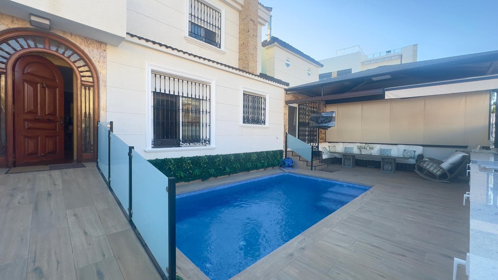 Casa Adosada en Esquina en Orihuela Costa – Urbanización Marco Polo A tan solo 1.500 metros del mar, en la codiciada Urbanización Marco Polo, se encuentra esta impresionante casa adosada en esquina, una propiedad que combina el encanto mediterráneo con la comodidad moderna. Reformada hace aproximadamente 20 años, se presenta hoy en día con un aspecto actual, funcional y perfectamente cuidado, lista para entrar a vivir sin necesidad de reformas. Exterior Privado y Zona de Ocio Nada más acceder a la parcela, destaca el espacio exterior privado, cuidadosamente diseñado para disfrutar al máximo del clima de la Costa Blanca. A mano derecha se encuentra una piscina privada de excelente tamaño, ideal para relajarse y refrescarse en los meses más cálidos. Junto a ella, una zona de barbacoa completamente equipada invita a compartir momentos con familia y amigos, mientras que un espacio chill-out techado aporta un ambiente relajado y acogedor, perfecto para las tardes de verano o reuniones al aire libre. La vivienda cuenta además con puerta de garaje en la misma parcela, proporcionando comodidad y seguridad al poder estacionar el vehículo dentro de la propiedad. Planta Baja: Amplitud y Confort En el interior, la casa ofrece un salón amplio y luminoso, presidido por una chimenea funcional que aporta calidez en los meses de invierno y realza el carácter acogedor de la vivienda. En esta misma planta encontramos un aseo de cortesía, un dormitorio de invitados ideal para familiares o visitas, y una cocina independiente completamente equipada, que comunica con un comedor adicional y un baño con plato de ducha. Desde esta zona se accede directamente al jardín trasero, donde se ubica nuevamente la zona chill-out, creando una perfecta continuidad entre interior y exterior. Planta Superior: Espacios Privados y Luz Natural Subiendo a la segunda planta se ubica el dormitorio principal, con baño en suite y balcón privado, ofreciendo un ambiente íntimo y confortable. En esta misma planta encontramos un segundo dormitorio doble, otro baño completo con plato de ducha, y un tercer dormitorio amplio que dispone de terraza acristalada con salida a una terraza abierta, ideal para disfrutar del sol durante todo el año. Equipamiento y Detalles Adicionales Todas las estancias de la vivienda cuentan con aire acondicionado, garantizando confort térmico tanto en invierno como en verano. La urbanización Marco Polo dispone además de una piscina comunitaria, aunque esta propiedad destaca precisamente por su piscina y espacios privados, que aportan exclusividad y mayor independencia. Ubicación y Entorno Situada en una zona tranquila y bien comunicada de Orihuela Costa, la casa se encuentra cerca de playas, centros comerciales, restaurantes y servicios, lo que la convierte en una opción ideal tanto como residencia habitual como vivienda vacacional o inversión con alta rentabilidad. En resumen: Esta casa adosada en esquina representa una oportunidad única de disfrutar de una vivienda amplia, moderna, reformada y con espacios exteriores excepcionales, a solo unos minutos del mar. Una propiedad que combina comodidad, privacidad y estilo de vida mediterráneo en una de las zonas más demandadas de la Costa Blanca.