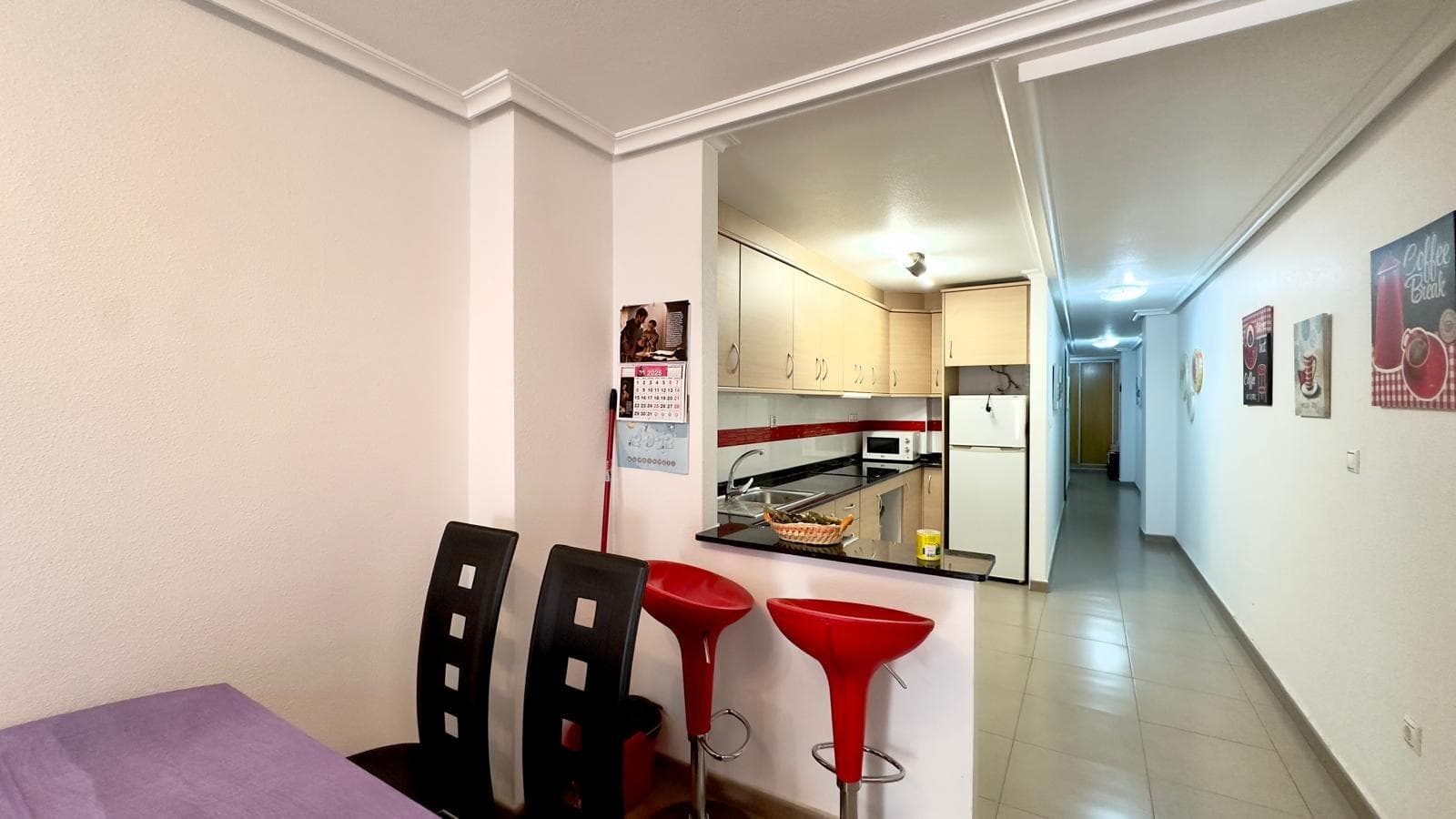 Уютная и функциональная квартира с 2 спальнями и 1 ванной комнатой на одной из самых центральных и востребованных улиц Торревьехи, известной улицей Калле Аполо, в нескольких минутах ходьбы от пляжа и в окружении всех удобств круглый год. Окружение и расположение Жизнь на улице Калле Аполо означает наслаждение аутентичным сердцем Торревьехи, в хорошо развитом городском районе с развитой транспортной инфраструктурой и широким выбором магазинов, супермаркетов, банков, кафе и ресторанов всего в нескольких шагах от вашей двери. Главные торговые улицы, такие как улицы рядом с набережной и площадью Конституции, находятся всего в нескольких минутах ходьбы, что позволяет вам совершать повседневные дела без необходимости в автомобиле. Пляж Плайя-дель-Кура и пристань для яхт также находятся в нескольких минутах ходьбы, что делает эту квартиру идеальным вариантом для тех, кто хочет сочетать городскую жизнь с близостью к морю на побережье Коста-Бланка. Здание и жилая атмосфера Квартира расположена в современном здании, типичном для центра Торревьехи, с ухоженным входом и преимущественно жилой атмосферой, где бок о бок живут семьи и молодые пары, а также иностранные жители, выбравшие город за его климат и качество жизни. Улица Аполо состоит из многоэтажных жилых домов с магазинами на первом этаже и квартирами на верхних этажах, создавая оживленную атмосферу днем ​​и спокойную ночью, идеально подходящую для постоянного проживания или в качестве второго дома. Это ровная, удобная для пеших прогулок территория с мощеными улицами и упорядоченной городской планировкой, облегчающая передвижение людей всех возрастов и делающая ежедневные поездки комфортными и приятными прогулками. Внутренняя планировка При входе в квартиру фойе ведет в гостиную, где гостиная-столовая расположена вокруг кухни открытой планировки, создавая единое просторное и практичное пространство, максимально использующее доступное пространство. Планировка естественным образом отделяет общественную зону квартиры от спальной зоны, где расположены две спальни и ванная комната, обеспечивая приватность для семей или тех, кто хочет совмещать жизнь и работу удаленно. Дизайн интерьера следует концепции функциональной городской квартиры с узкими коридорами и хорошо спланированными комнатами. Пропорциональность, разработанная для обеспечения комфорта в повседневном использовании без ущерба для отдельных зон отдыха и развлечений. Гостиная-столовая Гостиная-столовая — это сердце дома, светлое пространство, получающее естественный свет с балкона и идеально подходящее как для отдыха, так и для встреч с друзьями и семьей. Ее прямоугольная планировка позволяет разместить удобный диван напротив телевизора, а также обеденный стол на несколько человек, создавая универсальное пространство, которое адаптируется к различным стилям оформления, от самого современного до средиземноморского. Прямая визуальная связь с кухней открытой планировки и выход на балкон усиливают ощущение простора, делая это пространство естественным местом, где протекает повседневная жизнь, от неспешных завтраков до более приятных вечеров в компании. Оборудованная кухня открытой планировки В доме имеется оборудованная кухня открытой планировки, которая органично вписывается в жилую зону, предлагая комфортное и современное решение для тех, кто ценит практичность и прямой контакт с остальной частью дома во время приготовления пищи. Такая кухня облегчает общение с гостиной и обеспечивает легкий доступ к обеденной зоне. Гости или члены семьи могут наслаждаться едой во время приготовления, а дизайн позволяет естественному свету с балкона проникать в рабочую зону. Расположение мебели и столешницы спроектировано таким образом, чтобы максимально эффективно использовать пространство, обеспечивая организованную зону для приготовления пищи, подготовки продуктов и хранения, идеально подходящую как для отдыха, так и для круглогодичного проживания в квартире.