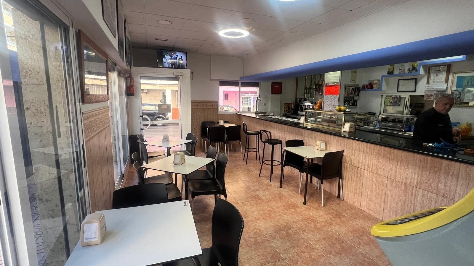 Se vende bar en funcionamiento en pleno centro de Torrevieja, una oportunidad perfecta para quien busca entrar en el negocio de la hostelería sin tener que empezar desde cero. No se trata de un simple local vacío, sino de un negocio vivo, con su ambiente, su clientela y su ritmo de trabajo ya en marcha. Al cruzar la puerta se percibe esa mezcla de energía y familiaridad que solo tienen los bares que llevan tiempo activos, donde los clientes habituales se sienten en casa y los nuevos visitantes encuentran un lugar al que saben que podrán volver. Es, en esencia, un proyecto listo para continuar, con todo preparado para seguir trabajando desde el primer día. Nada más entrar, el espacio transmite sensación de calidez y cercanía. La barra actúa como eje central del bar, ese punto de encuentro donde se apoyan los cafés de la mañana, las cañas del mediodía y las copas de última hora. Desde ahí se domina todo el local, se saluda a los clientes, se mantiene la conversación y se controla el ritmo del servicio. Es fácil imaginar el día a día: el bullicio suave de las primeras horas, cuando llegan los desayunos y los comentarios sobre la jornada; el ajetreo del mediodía, con tapas, bocadillos o menús rápidos; y el ambiente más relajado de la tarde, cuando algunos se quedan a alargar la sobremesa y otros entran buscando un rato de desconexión. El interior del bar está pensado para que la gente se sienta a gusto, tanto quienes vienen solos como quienes llegan en grupo. Mesas bien distribuidas, un ambiente que invita a quedarse un rato más de lo previsto y un aire de local de barrio que no renuncia a estar en pleno centro. La luz, el color y la forma en que se ha organizado el espacio crean una atmósfera que resulta cercana, sin pretensiones excesivas pero con identidad propia. Es el típico sitio donde los vecinos se citan sin tener que buscar referencia en el mapa, porque todos lo conocen, y donde quienes pasan por la zona se sienten cómodos entrando, aunque sea por primera vez. El hecho de que se venda con todo dentro es uno de los grandes puntos fuertes de esta oportunidad. Significa que el nuevo propietario no tiene que preocuparse por largos periodos de preparación, grandes inversiones iniciales en equipamiento o interminables trámites para dejarlo todo listo. Ya hay mobiliario, barra, maquinaria, utensilios y todo lo necesario para continuar con la actividad con una transición suave. Para quien quiera empezar cuanto antes, esto reduce el riesgo y acorta los plazos, permitiendo centrarse desde el primer momento en lo verdaderamente importante: la gestión del negocio, la atención a la clientela y la mejora progresiva de la oferta. El bar está en funcionamiento, lo que implica que existe ya un flujo de clientes, unos hábitos y una rutina comercial que pueden servir como base sólida. Esto es muy valioso tanto para alguien con experiencia en hostelería como para quien está dando sus primeros pasos en el sector, porque permite observar cómo funciona actualmente, qué franjas horarias son más fuertes, qué tipo de público lo visita y qué productos tienen mejor salida. A partir de ahí, el nuevo propietario puede decidir si mantener la línea actual, introducir cambios poco a poco o hacer una evolución más profunda del concepto, pero siempre partiendo de algo que ya está vivo. La ubicación, en el centro de Torrevieja, multiplica las posibilidades del negocio. Estar en una zona de paso, con actividad durante todo el año y con un entorno lleno de comercios, oficinas, viviendas y servicios, garantiza un flujo constante de potenciales clientes. Desde residentes que pasan a diario por la puerta hasta turistas que recorren las calles del centro, el bar se beneficia de una excelente visibilidad.