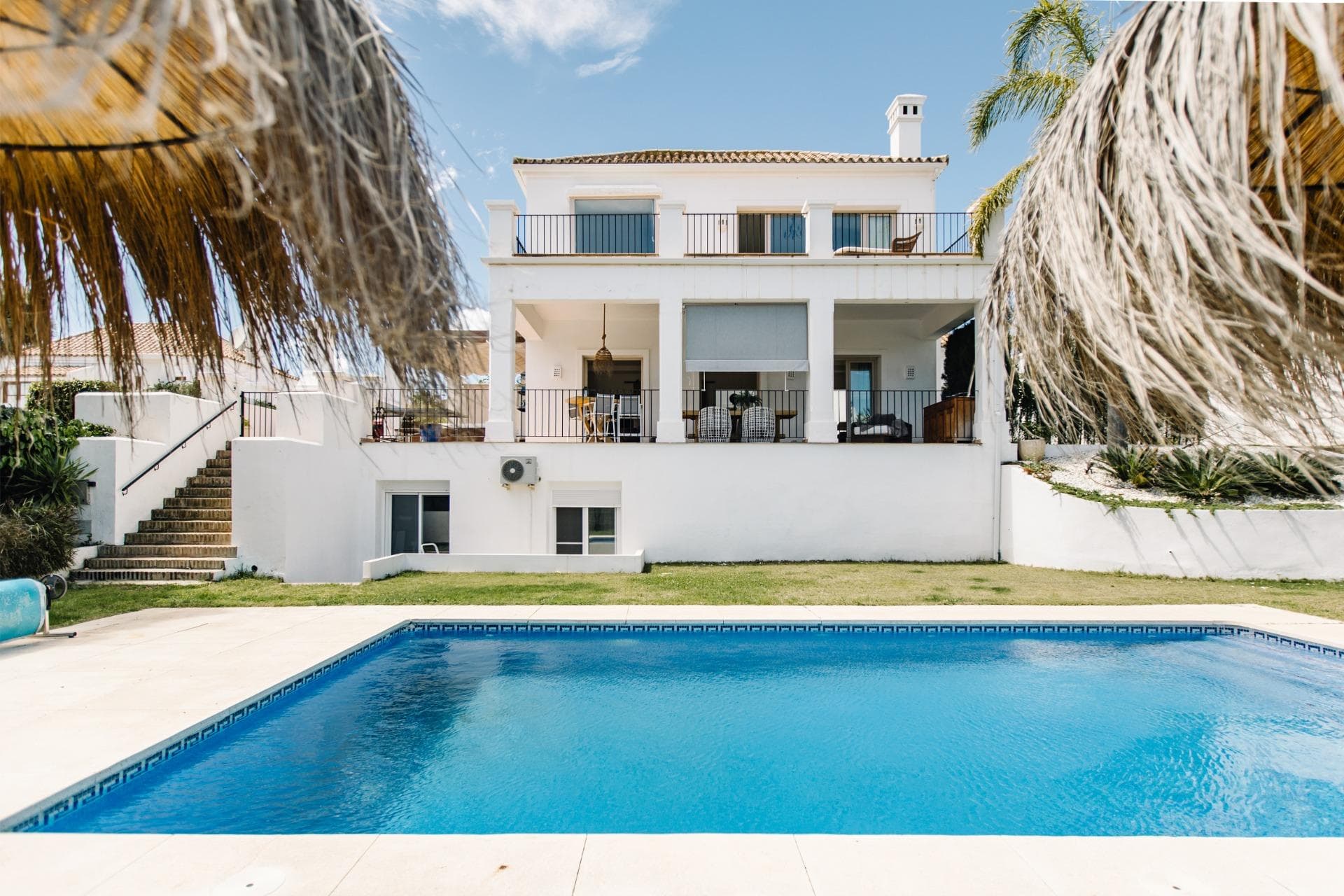 Welcome to this stunning 5-bedroom Andalusian-style villa, ideally situated on the first line of the prestigious La Resina Golf Course. Combining traditional elegance with modern comfort, this detached villa offers a peaceful and luxurious lifestyle on the Costa del Sol. Upon entering, you’re greeted by a grand entrance hall featuring soaring ceilings, a striking chandelier, and abundant natural light that immediately makes you feel at home. The villa is spread across three spacious levels. The main floor boasts a bright, open-plan living and dining area with direct access to the patio and terrace—perfect for entertaining or simply enjoying the serene golf course views. The charming outdoor space includes a BBQ area and lounge zones, surrounded by lush greenery. This level also includes a fully equipped kitchen, two guest bedrooms with en-suite bathrooms, and a guest toilet. Upstairs, the master suite offers a private sanctuary with a large en-suite bathroom, including a bath and walk-in shower, plus its own private terrace with panoramic views over the golf valley. The lower level features two more generously sized bedrooms, both with en-suite bathrooms, as well as a dedicated laundry room. Outside, the villa is surrounded by a beautifully landscaped garden with a heated saltwater swimming pool and multiple terraces that provide sun and privacy throughout the day. Conveniently located between Estepona and San Pedro de Alcántara, the villa is just a 4-minute drive from the beach, 13 minutes from the center of Estepona, and 14 minutes from Puerto Banús. This is a perfect home for those seeking elegance, comfort, and a prime golf-side lifestyle.
