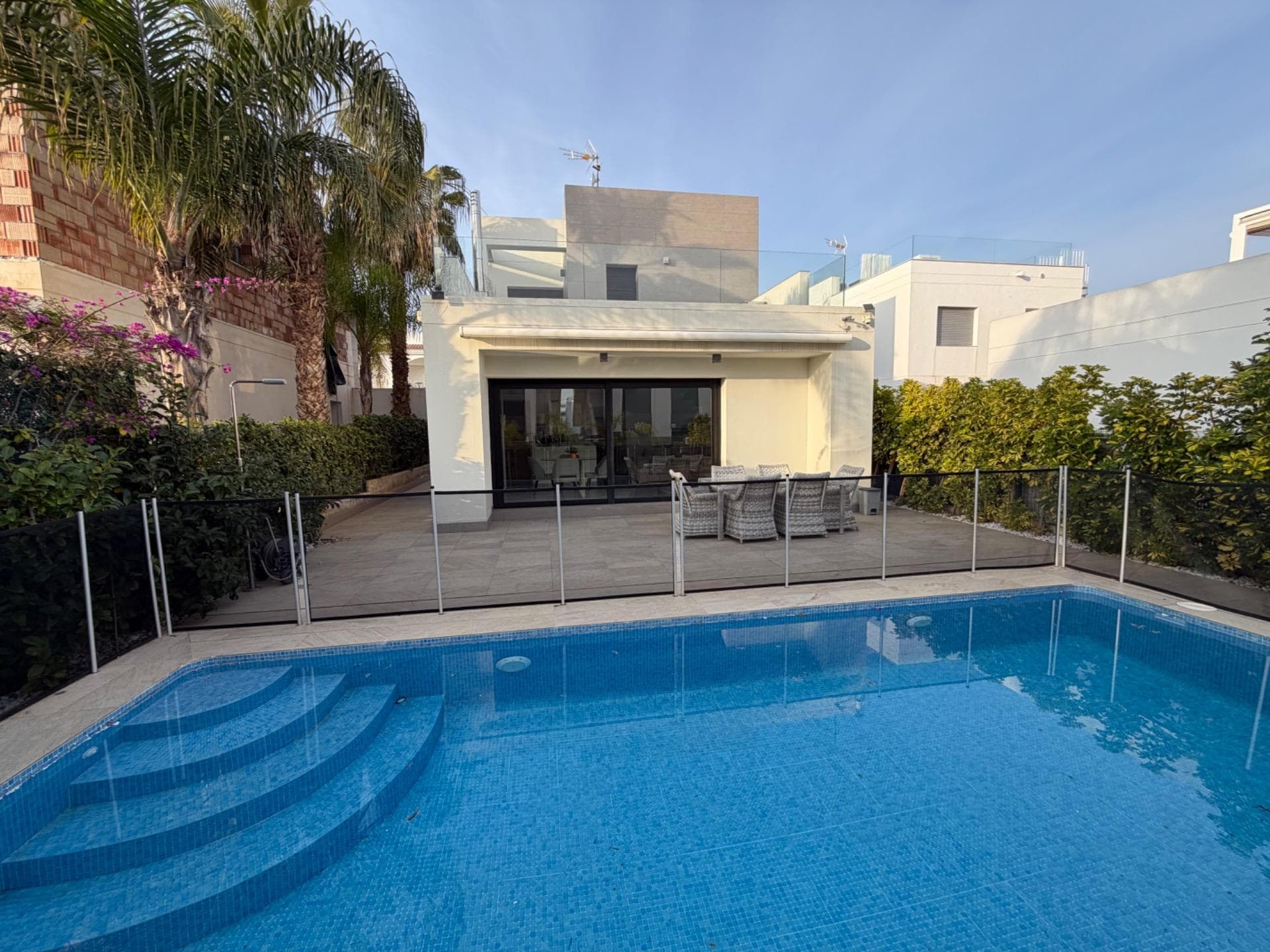 We are pleased to offer this beautiful modern detached villa, set in a quiet and well-located residential area. Designed for comfort, privacy, and easy Mediterranean living, this home is ideal for both permanent residence and holidays. Built in 2014, the villa sits on a 300 m² private plot and offers 125 m² of living space. The main floor features a bright open-plan living and dining area with a contemporary fully equipped kitchen, a master bedroom with dressing area, a full bathroom, and a guest toilet — all with direct access to the garden and private swimming pool. Upstairs, there are two spacious bedrooms, a complete bathroom, and access to a private terrace. From here, an external staircase leads to a large rooftop solarium, perfect for relaxing, sunbathing, or enjoying evenings with friends. The property has underfloor heating, central air conditioning, is sold fully furnished, and includes private parking. The landscaped garden and pool area create a peaceful space to enjoy the outdoor lifestyle all year round. A stylish, ready-to-move-into villa that offers comfort, space, and a true Mediterranean feel.