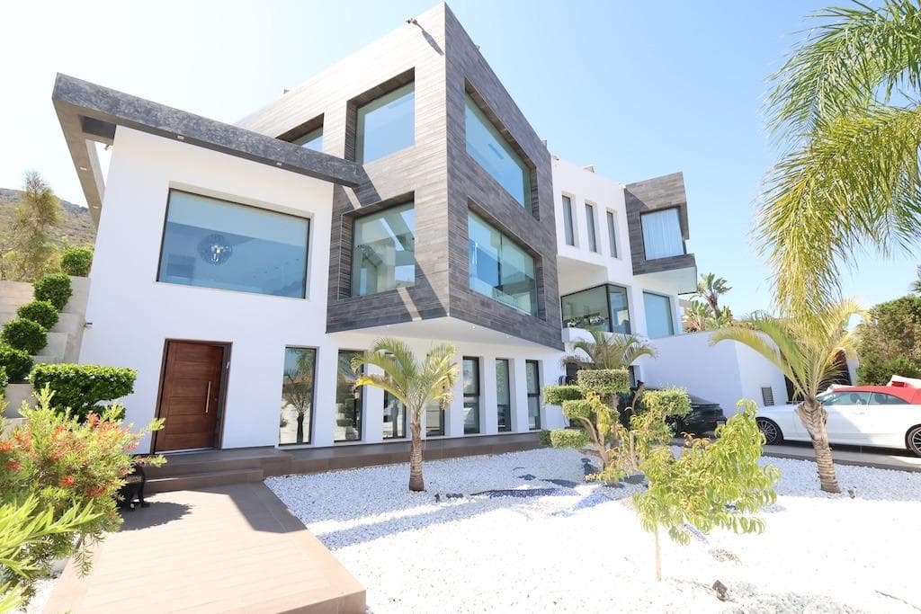 Discover the essence of modern luxury at Villa High, a stunning residence located in the exclusive Monte Olimpo residential area of Jávea. With 521 m² of built area spread over three levels, this property is a benchmark of architectural elegance, absolute comfort, and cutting-edge technology.. . The villa offers five en-suite bedrooms, each designed to guarantee privacy and maximum well-being. Its open-plan living space visually connects with the Mediterranean Sea and the imposing Montgó Mountain, creating a unique atmosphere where natural light and views take center stage. The fluid indoor-outdoor layout amplifies the feeling of exclusivity and harmony.. . Upstairs, an elegant loft with panoramic views provides the perfect space to work or unwind, ideal for those seeking to combine productivity with tranquility. The home also features a private spa with a heated pool and hammam, offering a sanctuary of relaxation without leaving home.. . The exterior of Villa High is a true oasis of privacy and comfort. Two strategically positioned pools blend seamlessly into the surroundings, while an outdoor jacuzzi invites you to relax under the stars. The summer kitchen with barbecue, accompanied by elegant chill-out areas, offers the perfect setting to enjoy the Mediterranean climate, cuisine, and lifestyle at its finest.. . On the lower floor, the private spa redefines daily wellness with a heated pool, hammam, fully equipped gym, and a multifunctional leisure room, turning every day into an experience of relaxation and self-care.. . Villa High is equipped with the latest technology: a home automation system, Sonos sound, an 18 kW solar system with batteries, an electric vehicle charger, comprehensive air conditioning, and a private garage. A home that combines sustainability, design, and sophistication in one of the most desirable locations on the Costa Blanca.