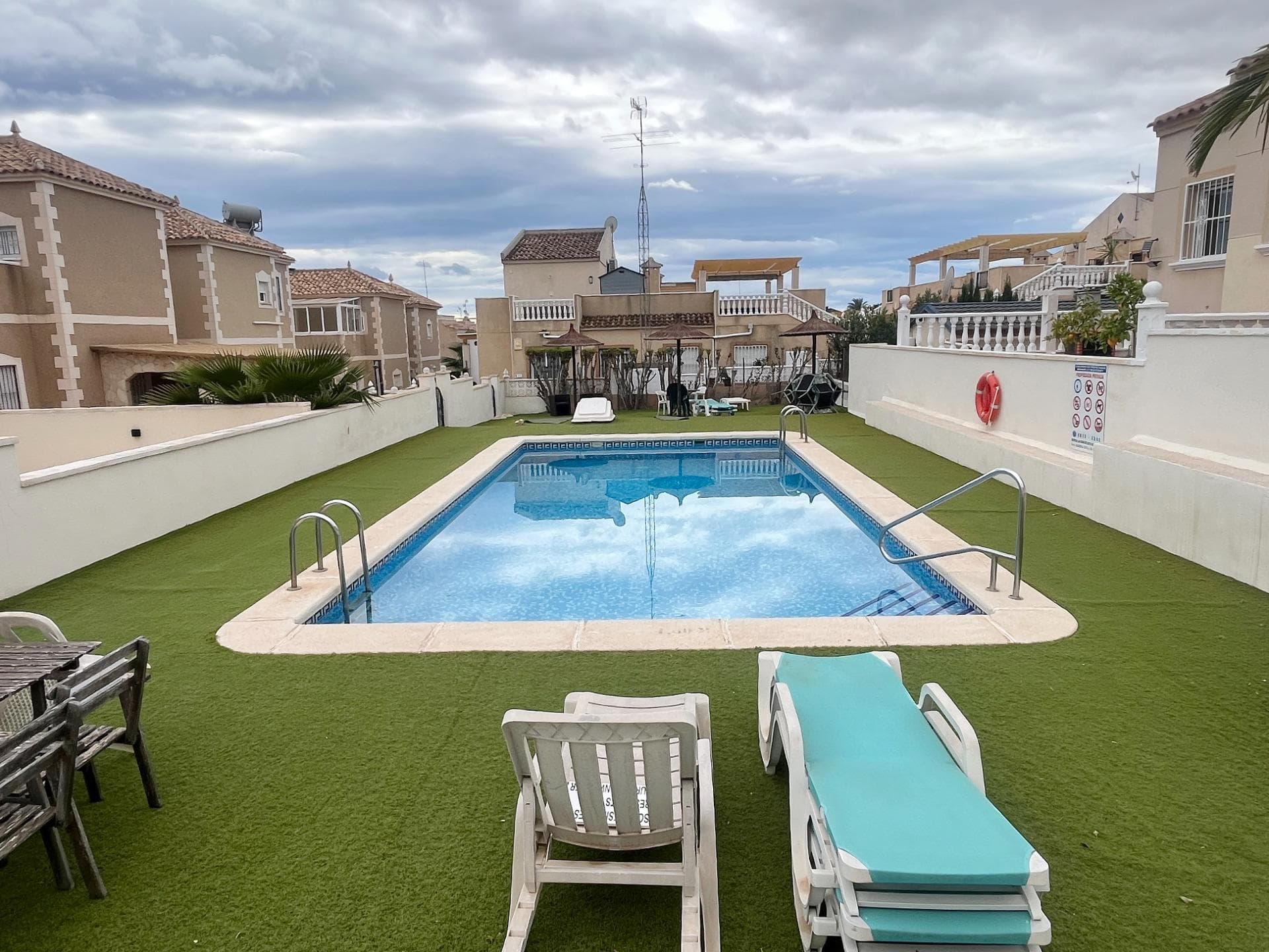Discover this spectacular villa located in the quiet town of San Miguel de Salinas. Upon entering, you will be greeted by a cozy porch, ideal for enjoying the outdoors. This property is distributed over two well-defined floors; the ground floor houses a bright dining room with air conditioning and windows equipped with bars and mosquito nets that provide security without sacrificing natural light. The open-plan kitchen is fully equipped and has access to a utility room where you will find space for laundry and additional storage. There is also a spacious bedroom with a built-in wardrobe, whose window offers views of the rear terrace of the home. The ingenious use of space is also reflected under the stairs, where you will find a practical storage room. As you climb the elegant wooden stairs to the first floor, you will find another single bedroom next to a full bathroom equipped with a bathtub. You will also have the pleasure of a spacious master suite that opens onto its own private terrace. From here, you can ascend to the upper solarium, whose unobstructed views allow you to glimpse the beautiful beaches near Torrevieja. The property also has sufficient private parking for two vehicles and includes direct access from one side to the common area: a refreshing swimming pool surrounded by landscaped areas ideal for picnics or family moments in the sun on well-maintained artificial grass. Located close to all essential amenities such as local supermarkets and prestigious schools such as El Limonar, this architectural gem is only ten minutes away from the Mediterranean Sea. An excellent choice if you are looking for tranquility combined with modern comfort.