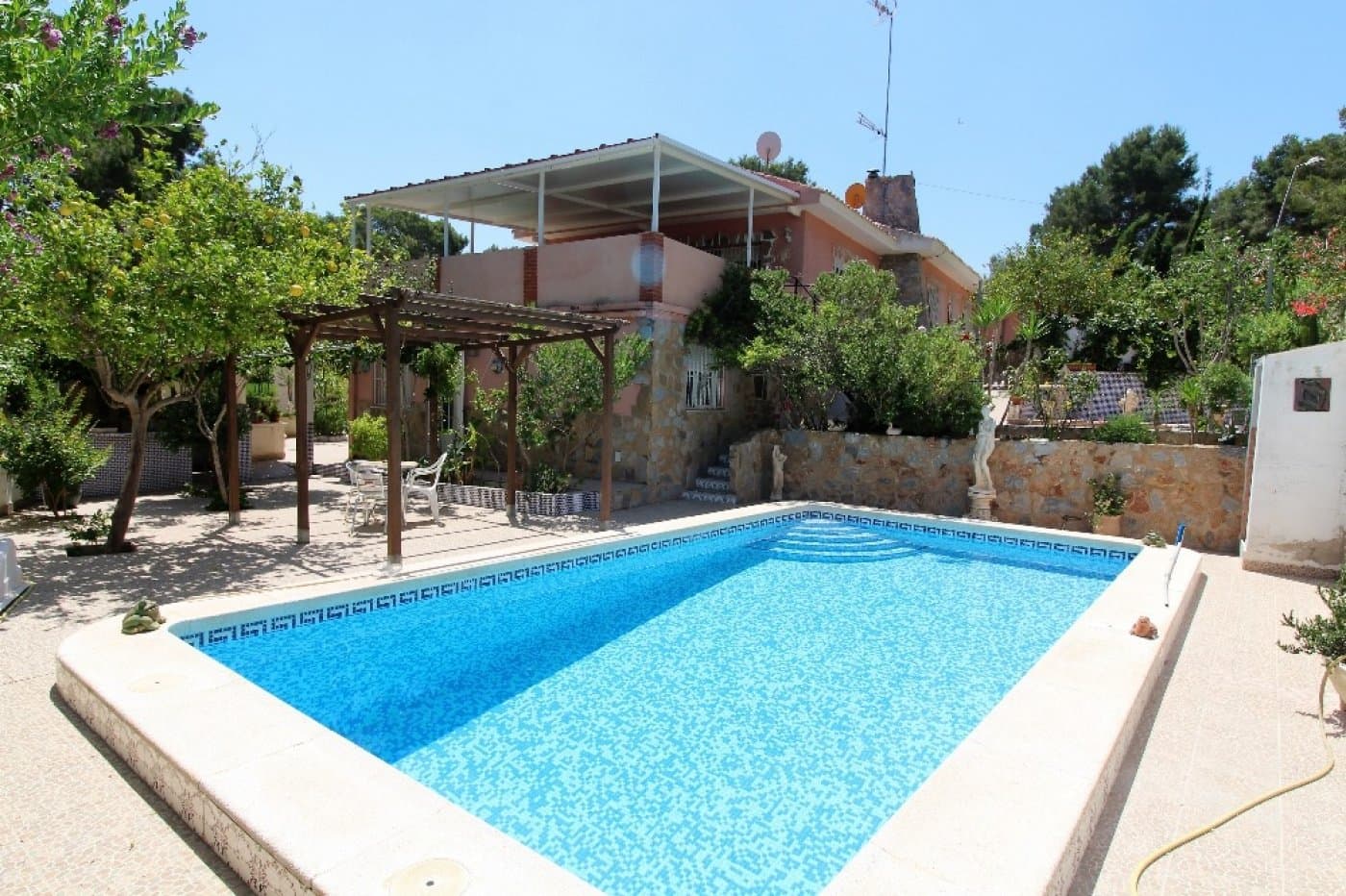 Independent Villa with spacious garden, terraces, swimming pool and garage on large plot. It consists of 2 houses: the main house on the ground floor and the other house on the semi-basement floor. The main house consists of a large living room with chimney and huge terrace, a fully equipped independent kitchen with access to the garden, 3 double bedrooms with fitted wardrobes and 2 bathrooms (one in suite with main bedroom). Furnished. Air conditioning. Heating. The other house on the semi-basement, attached to the main house, consists of a living room, a small kitchen, 2 double bedrooms with fitted wardrobes and a bathroom. Furnished. Ideal as a guest house! All located on a plot of approximately 900 m2 with gardens, terraces, trees, BBQ, swimming pool, 2 garages (one with complete bathroom), room for storage, in quiet environment.  Near all services, restaurants, supermarket, chemist and about 3 km from the beach.  Access to the AP7 motorway that connects with the Airports of Alicante and Murcia at 1 km.
