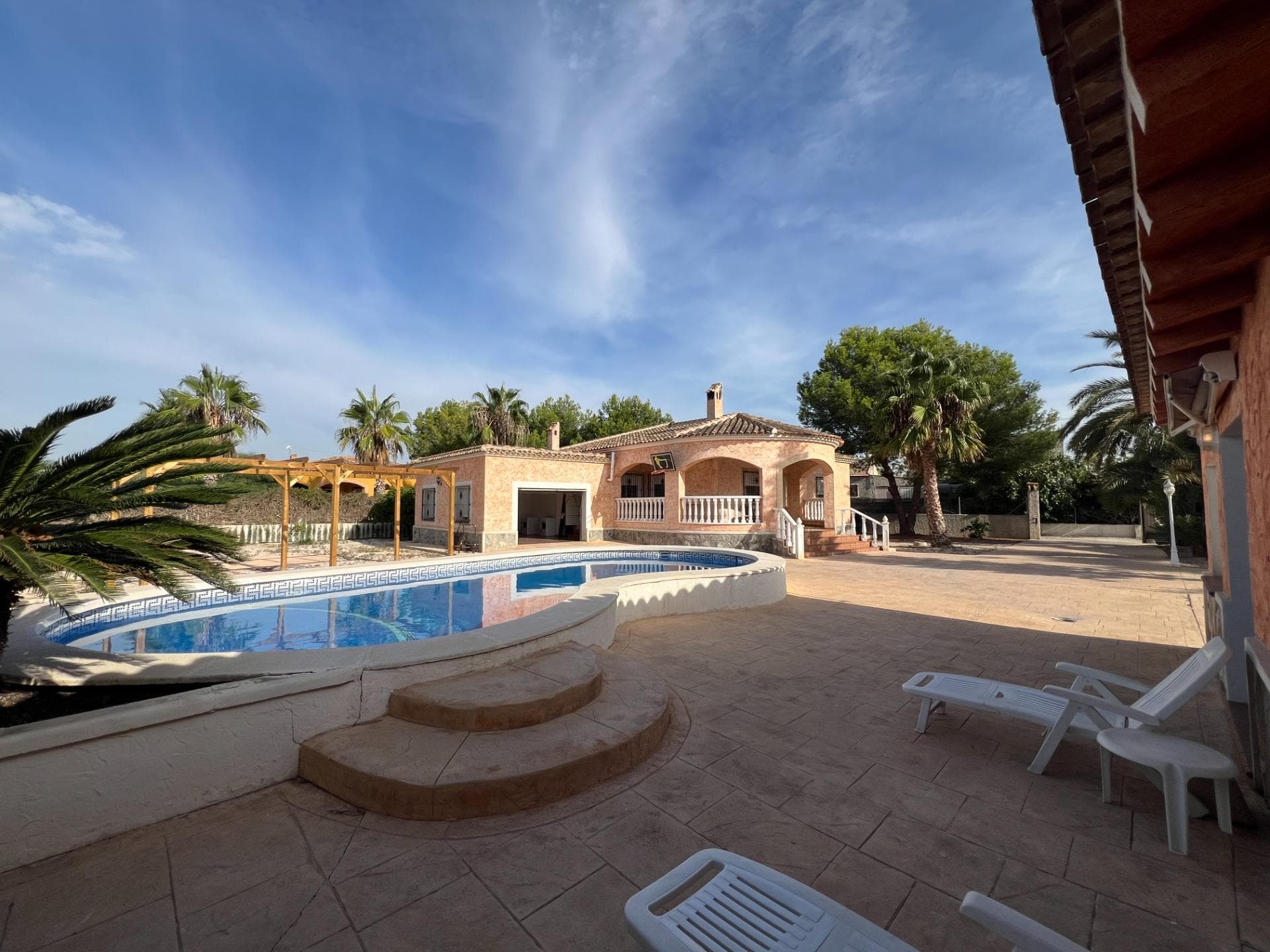 Detached 3 bedroom Villa in Dolores, ALICANTE. The property is bright, well-maintained and spacious with large kitchen, lounge/diner, 3 bedrooms - 2 have fitted wardrobes, one has private bathroom There is also an additional family bathroom. Access from the kitchen into integral double garage. A covered porch area is ideal for outdoor dining. The pool area is within the 2500 m2 walled part of the 9500 m2 plot with fruit trees and mature shrubs. An outbuilding has a summer kitchen, BBQ, dining area and WC. The location is peaceful and surrounded by fields although only a short distance to town and all amenities. Conveniently situated within short drive to beaches and easy motorway access to Alicante/Elche Airport and beyond!