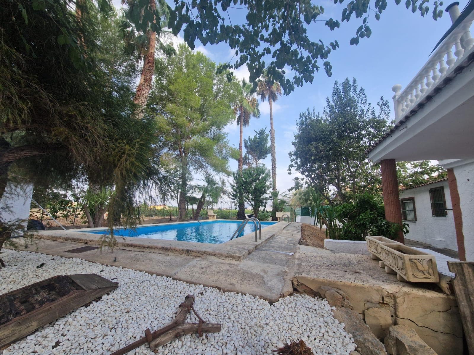 We are excited to present this fantastic Villa in the sought-after Huerta de Orihuela, just 30 minutes from the coast. This property, with 250 useful meters, with a garden of more than 1,000 m2, stands on a large plot of almost 12,000 m2. Its beautiful exteriors are full of vegetation and large trees, where we also find a swimming pool and a large sunny terrace, from which you can enjoy the good temperatures that the Vega Baja del Segura offers us all year round. The first floor consists of 3 bedrooms, 2 bathrooms, a fully equipped and furnished independent kitchen and a large living-dining room with direct access to the garden. On the second floor we find two more bedrooms and a bathroom. The property is presented in perfect condition, and decorated with exquisite taste.