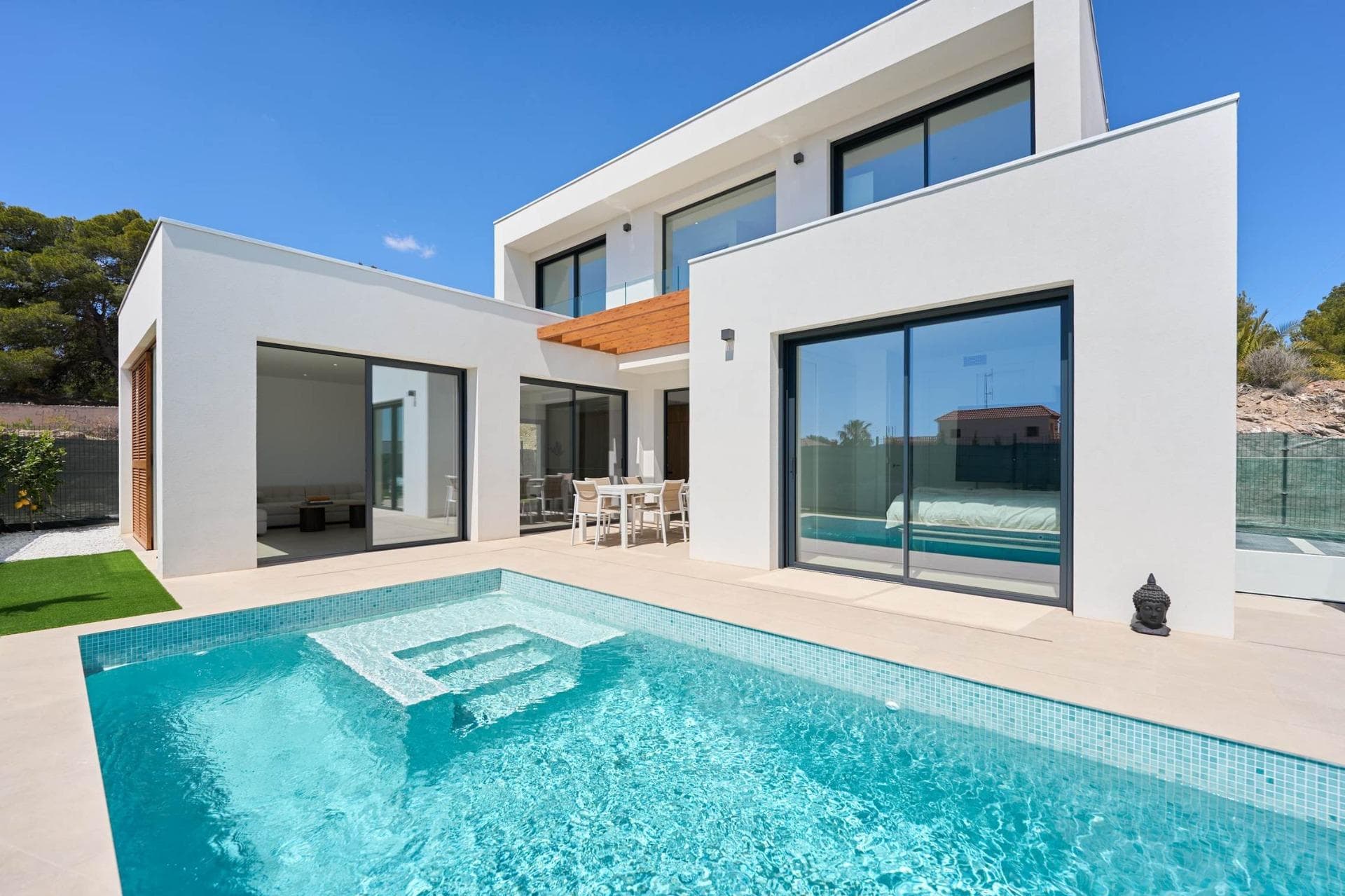 NEW BUILD VILLAS IN ALFAZ DEL PI

New Build private urbanization of 12 villas with their own swimming pool and garden, located in one of the most exclusive areas of the Costa Blanca, Alfaz del Pí. 

New Build exclusive development that offers you a unique, familiar and natural environment in a privileged area close to all the necessary services to offer you tranquility and wellbeing. 
The unique design of its wooden structure, with straight, Mediterranean lines, gives it the warmth and harmony needed to make you feel part of nature while optimizing resources, making the villas more sustainable and efficient spaces.

One of our guidelines when creating our development was the integration of our villas in nature, taking into account the surrounding green area, with the intention of increasing your quality of life and maximizing the positive influence on it.

Houses designed taking into account the smallest details, its wooden shell, its bioclimatic pergola, the solar panel system and the efficient and stylish mallorquinas offer you the most exclusive option for sustainable housing.

Open spaces full of light, great amplitude and no visual barriers, providing a sensation of infinite space. Large windows with direct access to the pool and garden area. The spacious living room with open kitchen makes it the ideal place to share with family and friends.

High-quality kitchen units with porcelain worktops and highly energy-efficient appliances.

Designed with the aim of providing the maximum harmony and balance necessary for a perfect recovery of both body and mind. With large floor-to-ceiling windows, the master bedroom has direct access to the swimming pool and garden area, which provide the extra comfort and relaxation so necessary for good rest.

The bedrooms on the upper floor of the villa have been designed to maximize the astonishing views of the Mediterranean Sea and the beautiful Sierra Helada.

Designed to create refuge spaces. The natural and warm tones are 
the protagonists, providing a sense of purity in the environment, 
optimising moments of enjoyment and relaxation and disconnection from the outside world. The Italian shower, the taps with water consumption reduction system, the furniture with built-in washbasins and the suspended sanitaryware make up a functional space positioning us at the forefront of the sector. 

Unique and innovative project based on minimum environmental 
impact promoting lower CO2 emissions in its construction, minimum energy consumption and a more sustainable and efficient use of resources.
Project takes an important step towards environmental awareness. The wood used in the whole shell of our villas comes from forests whose logging is authorized and ensures reforestation, sustainability and protection of biodiversity. The use of this material in the construction of your new home brings with it a series of advantages that have a direct impact on both your wellbeing and the construction quality.

Our homes are highly energy efficient, offering greater thermal and 
acoustic insulation, while maintaining the quality of the air inside the house and providing ideal natural lighting. The materials used in their construction are of high quality, durable and resistant to fire and humidity. 

Homes development is located in the well-known Scandinavia area of Alfáz del Pi. Just a few kilometers away lies the beach of Albir, where its crystal clear waters and the Sierra Helada with endless routes and activities makes it considered one of the best areas of the Costa Blanca. 
Very close to the Villas the urban center of Alfaz del Pí is situated, which meets all the necessary requirements for your new home, such as the extraordinary climate, with more than 300 days of sunshine a year, its gastronomic offer, the quality of its services and the magnificent relationship with the environment. 
There are also two prestigious Norwegian Schools as well as a Scandinavian club that already exists for half a century.