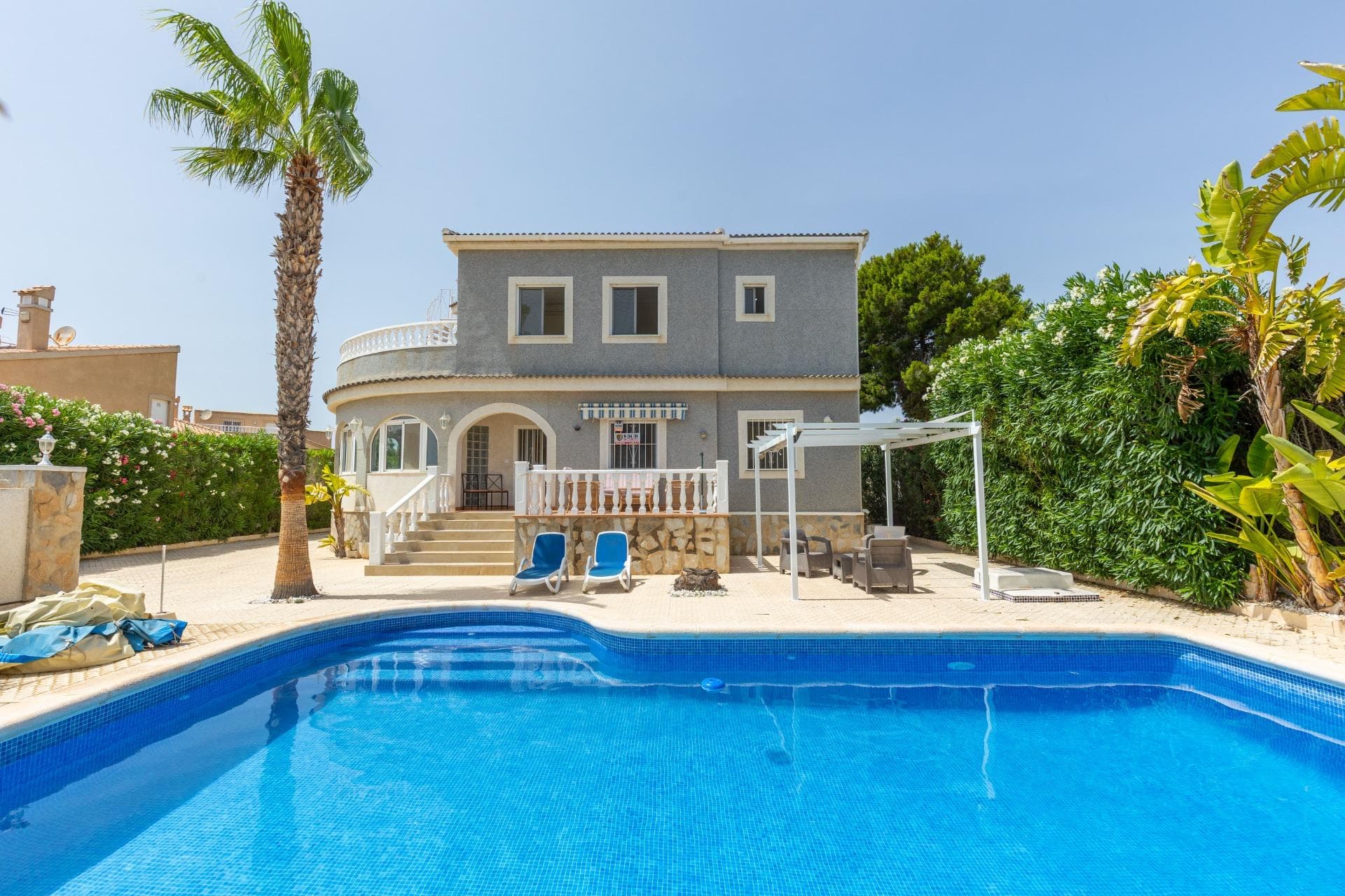 We present this impressive detached villa set on a 885 m² private plot, located in a peaceful residential area of San Fulgencio. The property features 5 bedrooms and 5 bathrooms, including one located outside — perfect as a pool bathroom or for guest use — making it ideal for large families or as a spacious holiday home. Inside, the home offers a bright and spacious living room with fireplace, an independent dining area, fully equipped kitchen, and a glazed porch for year-round enjoyment. There is also a laundry and storage area, along with a private terrace and solarium to enjoy the Mediterranean climate. The exterior is truly exceptional: private pool, large and well-maintained gardens, and a closed garage with space for two cars. A charming property offering privacy, space and comfort — perfect for those seeking a peaceful lifestyle without giving up nearby amenities.