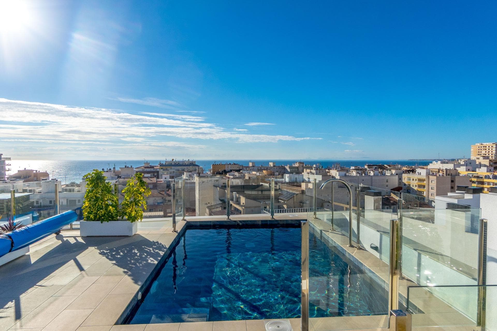 This modern apartment offers a functional and bright design in a highly convenient area of Torrevieja. It features two bedrooms, including the main one, and two contemporary bathrooms with glass screens and floating sinks—one finished in textured white tiles and the other with a wood-effect style. The bedrooms follow a balanced, minimalist decor, with large windows that provide natural light. A decorative embossed wall adds a distinctive touch. The open-plan living area includes a comfortable lounge, TV unit, and floor-to-ceiling sliding doors leading to the balcony. Neutral tones and light ceramic flooring contribute to a modern, clean look. The layout makes excellent use of the space, offering an elegant and practical home. The building includes a communal rooftop solarium and pool. Located close to all services and just a 4-minute walk to the city centre.