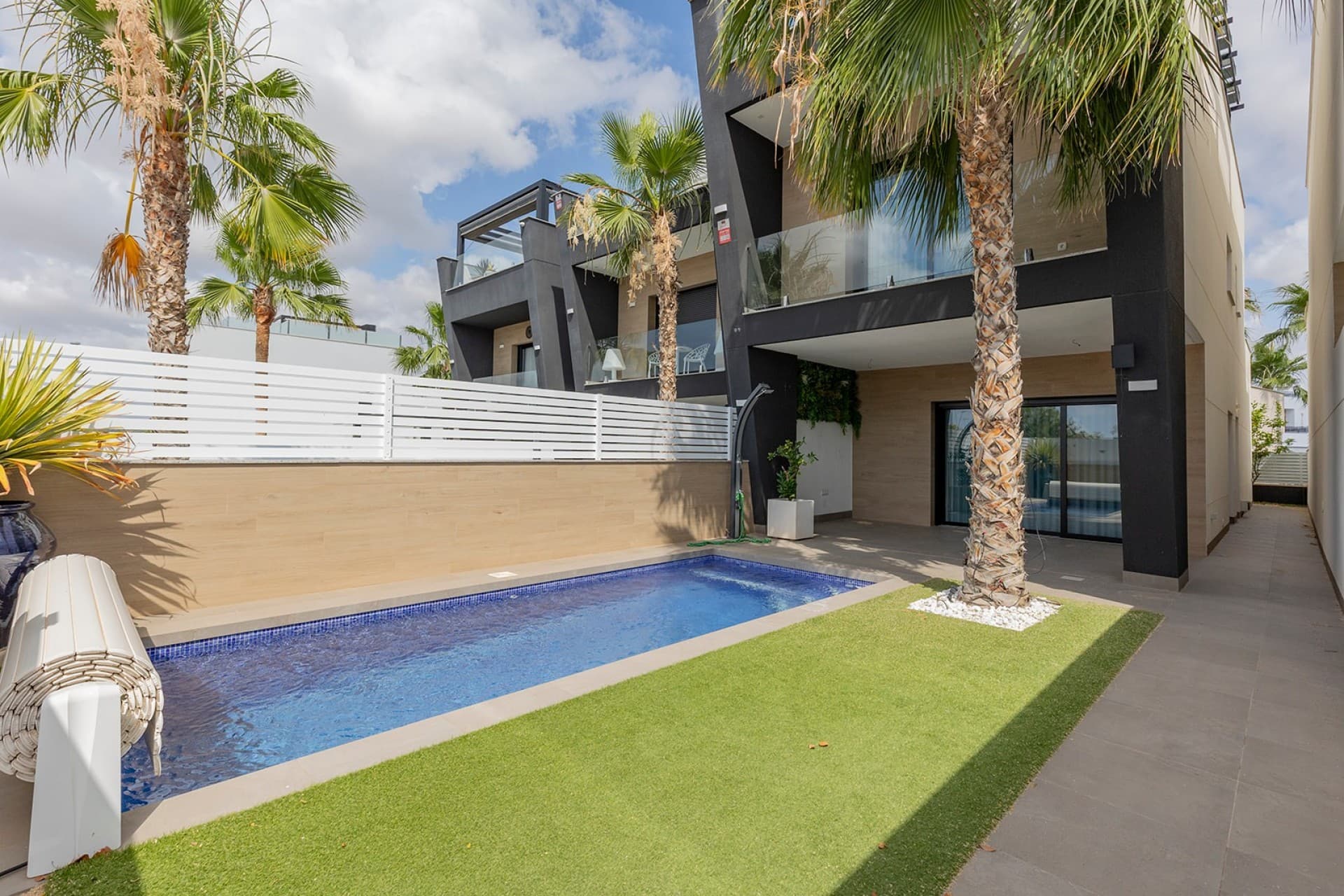 Discover this beautiful, move-in-ready new-construction villa in the beloved town of Benijófar, a charming Spanish village on the Costa Blanca where tranquility, comfort, and all amenities are within easy reach. The beach at Guardamar del Segura is just a 15-minute drive away.This modern home combines high-quality finishes with a well-thought-out layout and offers everything you need to fully enjoy the Mediterranean lifestyle.Upon entering, the impressive living area immediately catches your eye with its double-height ceilings, large windows, and abundant natural light. The open layout creates a sense of spaciousness and ensures a seamless connection between indoors and outdoors.The modern open kitchen with a cooking island forms the heart of the home and is perfect for enjoying time with family and friends. Adjacent to it is a practical separate storage/laundry room with a connection for a washing machine and extra storage space.The villa features three comfortable bedrooms, two stylish bathrooms, and a separate guest restroom. Thanks to the high-quality materials, built-in closets, and modern finishes, you’ll enjoy optimal living comfort here.Outside, you’ll find a low-maintenance garden with a private pool, where you can relax in complete privacy and enjoy the wonderful climate of the Costa Blanca. The spacious terraces offer various spots for sunbathing or socializing.The absolute highlight of this home is undoubtedly the spacious rooftop terrace with an outdoor kitchen. Here, you can enjoy a stunning unobstructed view of the lush surroundings and savor long evenings, cozy dinners, and breathtaking sunsets all year round.In addition, the home is equipped with solar panels, which not only help lower your energy bill but also contribute to a sustainable and forward-thinking lifestyle.Key FeaturesMove-in-ready new-construction villa3 bedrooms2 bathroomsSeparate guest restroomPrivate poolSpacious and bright living room with double-height ceilingsModern open-concept kitchen with a cooking islandSeparate storage/laundry room next to the kitchenBuilt-in closetsLarge private rooftop terraceOutdoor kitchen on the solariumUnobstructed views of green surroundingsSolar panelsIntegrated air conditioningHigh-quality finishesLow-maintenance gardenLocated near shops, restaurants, sports facilities, and golf coursesThis stylish villa is ideal as a permanent home, vacation home, or investment and offers a perfect combination of luxury, comfort, and energy-efficient living in an excellent location on the Costa Blanca.Contact us today for more information or to schedule a viewing of this unique property in Benijófar.