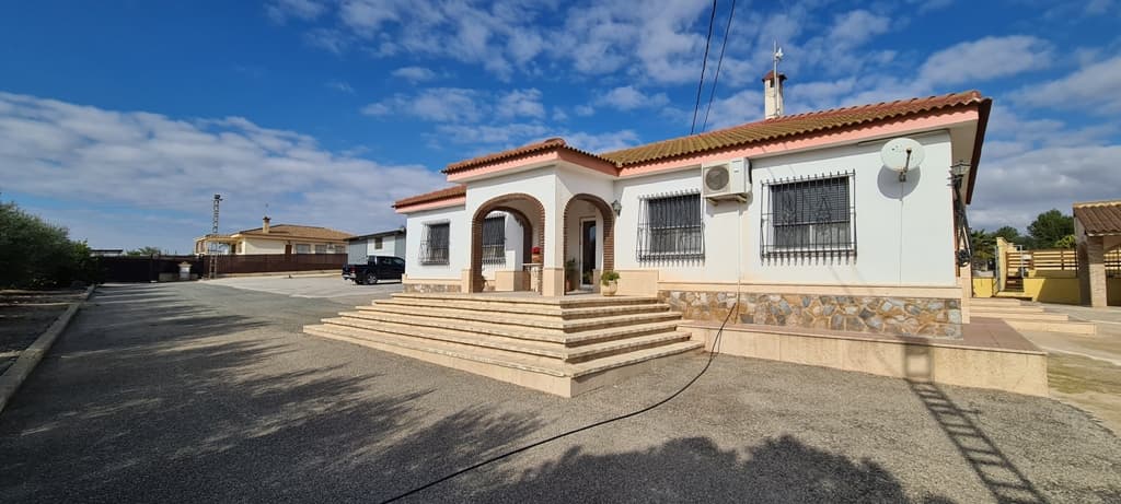 This charming typical Spanish villa is located on a large property of 10,000 m² and is ideal, for example, for an entrepreneur who needs a lot of work space but also wants to be close to the private home and the family.

 A completely closed workspace of 400 m², a covered workshop outside, numerous storage rooms and storage areas, .. in short, too much to mention but absolutely worth it! If you do not need these workspaces, you can also turn them into an extra home if you wish.

 The private house has a total habitable surface of 330 m², all on one floor and consists of a very spacious kitchen with closed fireplace, a large storage / laundry room, a sitting room, lounge - dining room, 2 entrance halls (front and rear), 2 bathrooms, 3 bedrooms , a large walk-in dressing room and a beautiful covered terrace.

 There is central heating.

 The house has an exceptionally large basement which can be used for many purposes. The technical room for the swimming pool is located in a separate part of the basement.

 The private outside area also contains a beautiful outdoor kitchen with authentic wood-burning ovens, griddle, fireplace, etc.. And behind it is a beautiful fenced relaxation area with heated swimming pool with built-in jacuzzi elements at the staircase and a jetted waterfall. There is also a covered outdoor area and a bathroom/dressing room with shower and toilet.

 The domain is secured with an alarm system with cameras.

 The entire estate is described in 2 deeds.

 The total annual Suma (land tax) is about 1000 €

 Do not hesitate to contact us for further information or viewing.

