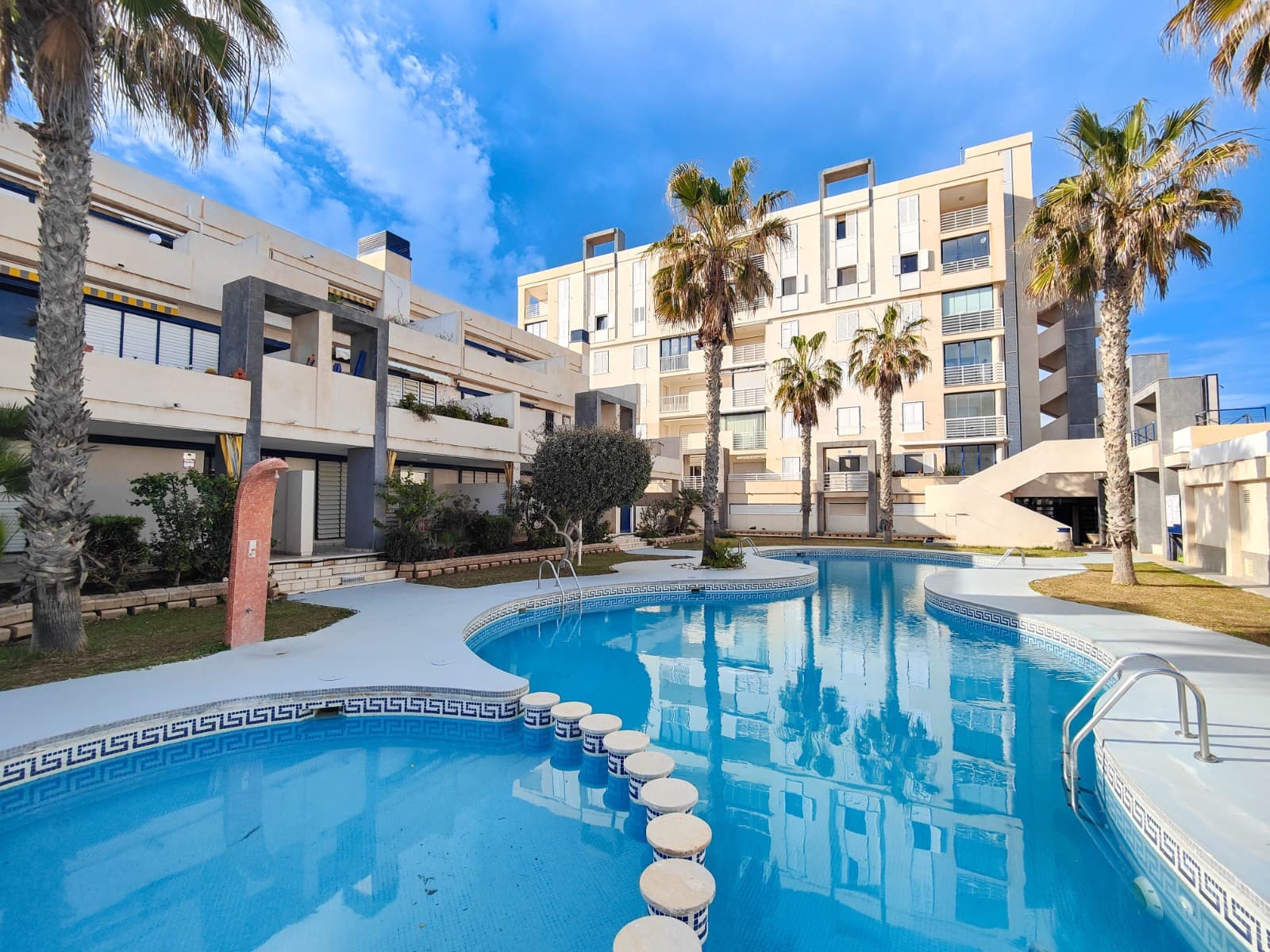 Exclusive ground floor corner apartment for sale in a closed front line residential at the La Mata Beach, one of the most sought-after areas of Torrevieja.The property features a spacious south-facing terrace of around 18m², overlooking the green areas of the residential complex. The perfect place to enjoy the sun all year round, have breakfast outdoors or relax after a day at the beach.The apartment includes 2 bedrooms with built-in wardrobes, 1 good size bathroom with walk-in shower, and an open-plan kitchen connected to the living room. The property has been partially renovated, including windows, flooring, electrical installation and bathroom.It is sold fully furnished and equipped with white goods, making it ready to move in.The property offers a lot of extras such as air conditioning, electric heating, electric shutters, security door, awnings, and much more.The residential complex offers a beautiful environment with a communal swimming pool surrounded by natural grass, palm trees and a pond, creating a true Mediterranean oasis.There is a small communal parking area outside the complex, a huge communal solarium with views over the La Mata beach, a social club and a concierge. The location is exceptional: the building is frontline, with direct access to the promenade and the La Mata beach, both just 50 metres from the apartment.An excellent opportunity as a holiday home, rental investment or permanent residence by the sea.