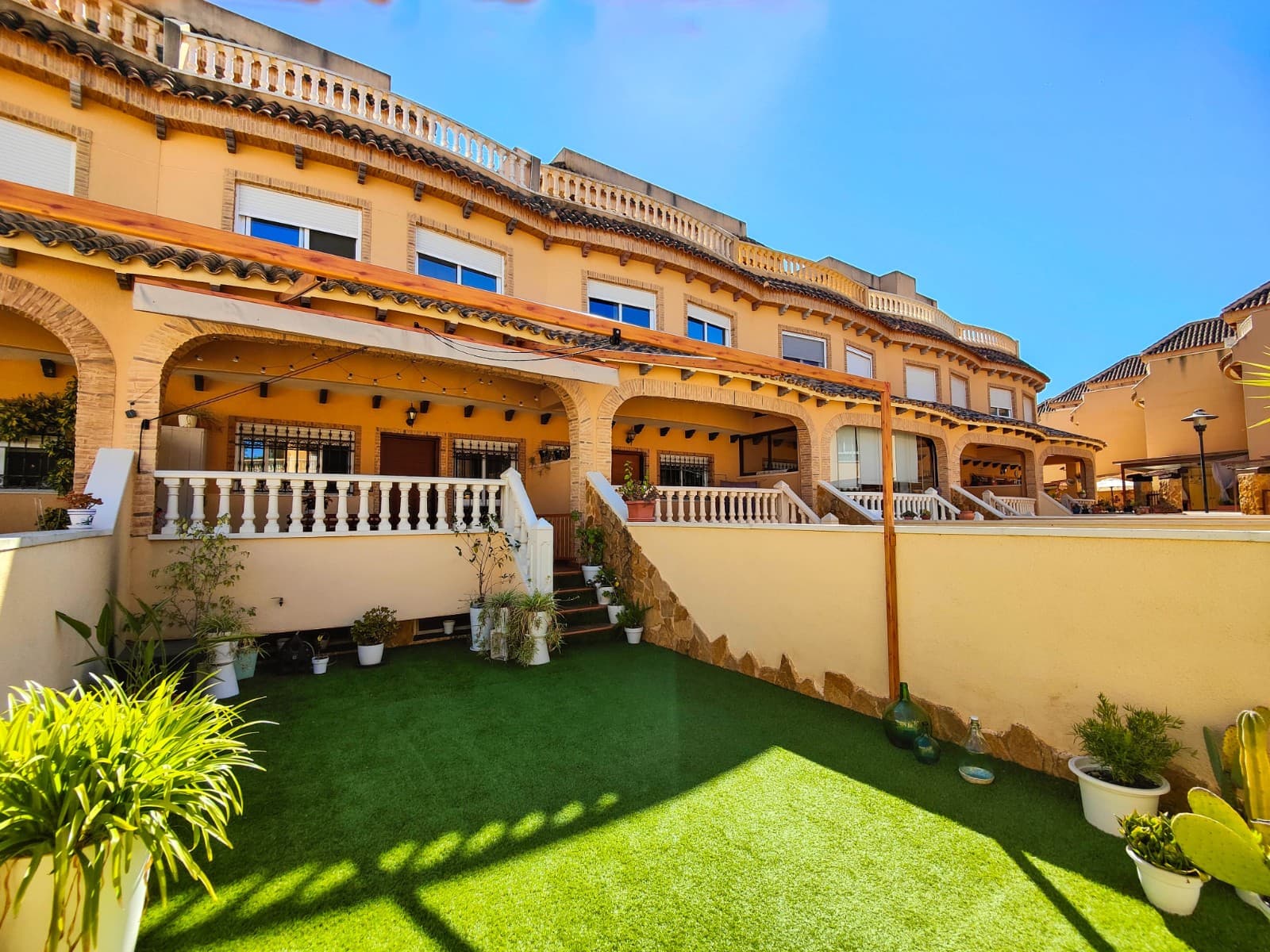 Discover this beautiful partially renovated townhouse for sale in the peaceful Los Estaños area, within the Montegranados Residential complex in Guardamar del Segura. A spacious and bright property ready to move into, ideally situated just 2 km from the beaches of Guardamar and only 1 km from the town centre with all amenities nearby.The property offers 108 sqm built area distributed over several levels designed for comfort and practicality. The basement level features an additional living room, a full bathroom with shower and a convenient storage room, making it perfect as a guest area, entertainment space, an extra bedroom or storage.On the main floor, you will find a spacious and very bright living-dining area with a fully renovated open-plan kitchen in modern white finishes, equipped with stainless steel appliances and a dishwasher. There is also a guest toilet on this level. The grey laminated flooring throughout the property adds a contemporary and stylish touch.The first floor consists of 2 bedrooms and 1 full bathroom. The master bedroom benefits from plenty of natural light and includes two built-in wardrobes. The second bedroom has access to a covered interior patio currently used as a laundry area.The top floor features an additional room currently used as a home office, although it can easily be converted into an additional bedroom. From here, you have access to the private solarium with open views, ideal for enjoying the Mediterranean climate all year round.Outside, the property offers a 43 m² front garden with artificial grass and a lovely porch of approximately 15 m². The northeast orientation provides pleasant temperatures and natural light throughout the day.The property also includes a private parking space in the underground garage, air conditioning in every room, access to the communal swimming pool, and is sold partially furnished with appliances included.An excellent opportunity for permanent living, holiday use or investment on the Costa Blanca South.