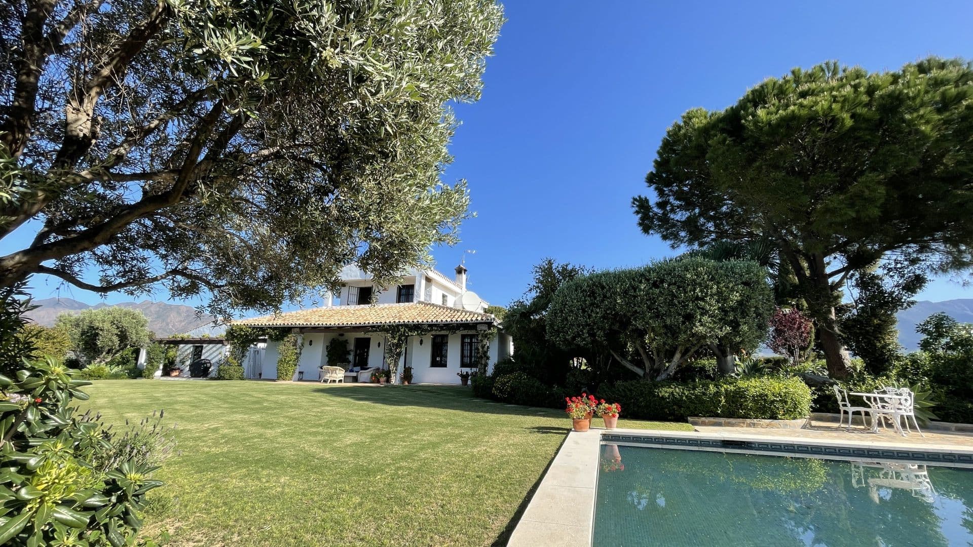 This elegant family home is just 10 minutes from the charming seaside town of La Cala de Mijas. This expansive property combines tranquillity with accessibility to beaches, shopping, international schools, golf courses, and equestrian facilities. Set in beautifully maintained gardens with mature landscaping, this home boasts breathtaking panoramic views of the Mediterranean Sea and the surrounding mountains. Its main entrance opens into a spacious gravel forecourt with electric gates, ample parking, and a warm entrance porch with traditional oak doors. The main house, built across two floors, includes: Ground Floor: A grand hallway with guest cloakroom, an expansive modern kitchen with a larder and breakfast/dining area leading to an outdoor terrace with stunning views. The formal sitting room features a large open fireplace and opens to a covered terrace with an outside lounge area, while the dedicated dining room and fitted study make it ideal for remote work. There is also a double guest bedroom with an en-suite bathroom. Top Floor: A luxurious master suite with vaulted beamed ceiling, en-suite bathroom, walk-in wardrobe, and a private balcony with sweeping valley views. Additionally, the villa has an adjoining self-contained guest wing with a sitting room featuring vaulted ceilings, two double bedrooms, a bathroom, and an open-plan kitchen leading to a charming, shaded terrace. This terrace offers an expansive dining area that can host many guests, surrounded by an intimate garden with stunning Sierra de Mijas views. The lush grounds include a private 10m x 5m swimming pool, a variety of flowering plants, shrubs, and fruit trees. A kitchen garden and orchard as well as a computerized irrigation system With Starlink satellite Internet, air conditioning, and an alarm system, this villa perfectly balances country living with modern conveniences. Located 10 minutes from Fuengirola, close to medical facilities, petrol stations, and just 30 minutes from Marbella and Malaga airport, it’s ideal for those seeking a serene yet accessible lifestyle. An adjoining plot offers potential for stables or a tennis court, adding further flexibility to this impressive property.