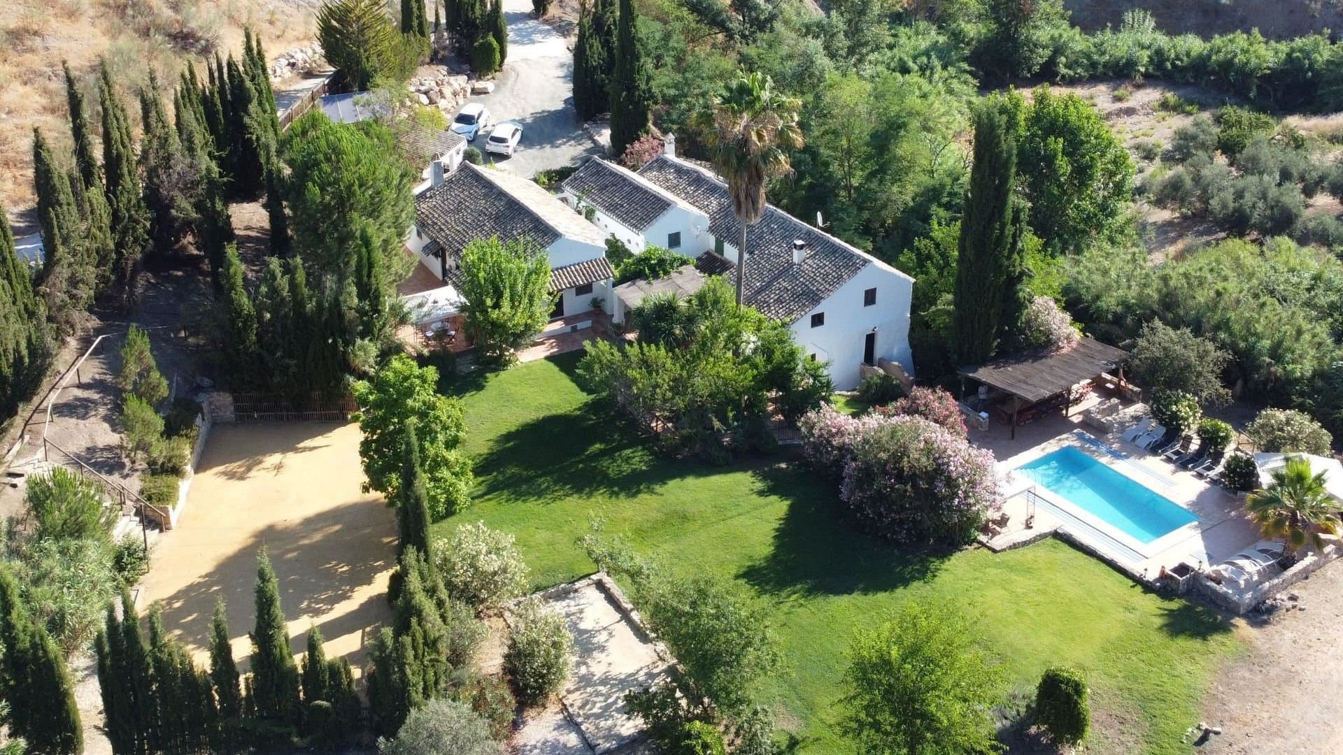 Una hermosa casa, antiguamente una molina, pero actualmente utilizada para un negocio de turismo rural, con 10 dormitorios, 7 baños y piscina privada, rodeada por grandes jardines privadas. ¡Es una propiedad fantástica que ofrece todo y más! La casa está rodeada de colinas y olivares cerca del encantador lago de Iznájar y con excelente acceso a las vibrantes ciudades del sur de España: Granada, Sevilla, Córdoba, Ronda y Málaga. Este singular y bello cortijo andaluz fue un molino de agua y una panadería en funcionamiento hasta los finales del siglo XX, suministrando pan a las granjas y pueblos alrededores. La cocina de la antigua panadería todavía cuenta con el horno de pan original, pero hoy también cuenta con un horno profesional y un lavavajillas. En el terreno, encontrará hierbas frescas del huerto, granados, higueras, melocotones y almendros, terrazas soleadas y una pista deportiva iluminada, ideal para jugar al tenis, al voleibol o al bádminton. También hay un estudio usado para cine en casa (cuenta con proyector y pantalla), yoga y pilates y hay una pista de petanca, tenis de mesa, arenero y, por supuesto, una preciosa piscina privada. El exterior también cuenta con zonas de comer a la sombra, lugares de picnic junto al arroyo, un patio cubierto de vides y grandes jardines privados donde los niños pueden correr sin peligro. El terreno es plano y sería ideal para los caballos. Restaurada con cariño para conservar todo el carácter de la antigua casa del molino, el alojamiento está distribuido en dos alas alrededor de un patio central. El ala oriental de la casa se ha renovado a partir del antiguo molino, conservando sus características originales, con la cocina principal, el salón y el comedor junto con 5/6 dormitorios y 4 baños. La otra ala era antiguamente la casa del jefe panadero y tiene 4 dormitorios, 3 baños y una segunda cocina. Esta impresionante propiedad ofrece la opción de desayunar en la terraza de la cocina (viendo las tonterías de los patos y escuchando a las gallinas poner sus huevos por la mañana), almorzar en el patio sombreado por las viñas, o pasear hasta el arroyo con los niños para tomar algo o hacer un picnic y disfrutar de la cena junto a la piscina por la noche. Si prefiere recibir a los invitados en el interior, el comedor tiene capacidad para 18 personas y puede extenderse fácilmente a la cocina adyacente de la antigua panadería, con capacidad para otros 10 invitados.