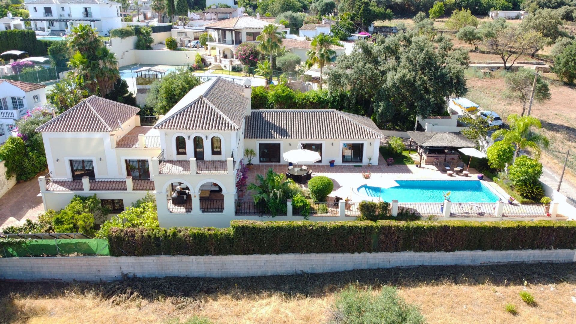 Outstanding villa with fantastic views, 4 bedrooms, pool and garage, located within walking distance of the town. Located in a quiet residential area this impressive villa has it all. As you enter the property through electric entrance gates you are immediately greeted by the stunning pool area and Tiki Hut style summer kitchen and bar. This makes an excellent entertaining area. The main door leads you into a grand entrance hall with double height ceiling. Upstairs is the master bedroom suite with full bathroom, dressing room, very spacious bedroom plus a balcony and a side terrace, both with incredible views. On the main floor there are 3 bedrooms, 2 bathrooms and WC. The third bedroom could be used as a guest annex as it has a living room with the bedroom upstairs and doors leading directly out to the terrace. The main living area is a huge and bright, dual aspect living-dining room with fireplace and leads to the luxurious fitted kitchen with central island, which in turn leads out to the pool and entertaining area. The lower ground floor has a 96m² basement, large enough for several cars or to covert to additional living space. There is also a machine room housing the technical equipment for the house. There are solar panels which run the underfloor heating, domestic hot water and the pool, depending on the time of year. The property has been built with first class materials and in addition to the underfloor heating, there is hot and cold air-conditioning throughout.