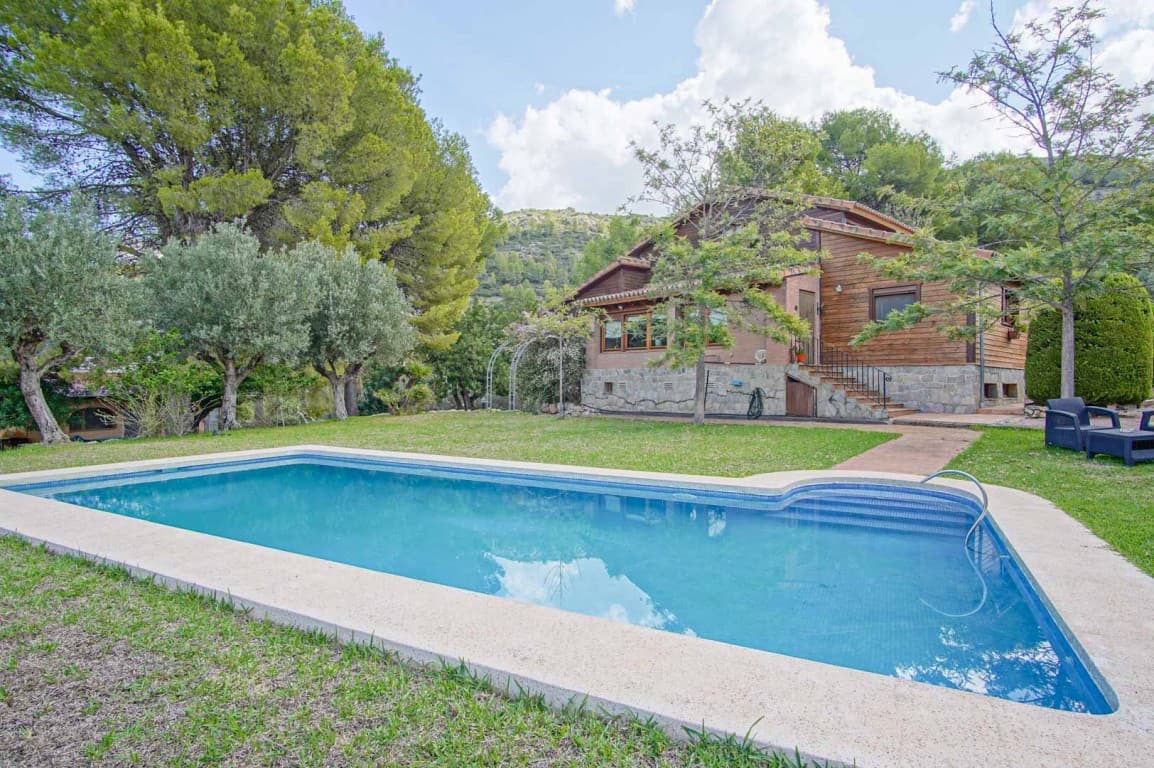 Experience the charm of this enchanting villa, built with noble materials such as Finnish pine and natural stone, nestled in the idyllic setting of Orba, Alicante. Situated on a mostly flat plot spanning nearly 18,000 m², this property is perfect for those who crave tranquility and a deep connection with nature.Ideal for animal and horse lovers, the estate comes equipped with stables, providing ample space for your pets to roam freely. As you enter the villa, you are greeted by a warm, inviting ambiance. The first floor features three spacious double bedrooms, one of which boasts an en-suite bathroom, ensuring comfort and privacy for family members or guests.The living-dining area, with its cozy central fireplace, is the perfect place to unwind while enjoying picturesque views of the lush garden and sparkling swimming pool. From this space, the surrounding valley and mountain landscape become part of the home, creating a serene and soothing atmosphere. The separate kitchen, complete with a pantry and laundry room, is designed for those who love to cook while basking in the peaceful ambiance of the countryside.On the upper floor, an expansive open space offers breathtaking views of the surrounding nature. Currently used as an office and reading nook, this area is ideal for creative work or quiet contemplation. The panoramic views from this level are truly spectacular, changing with the light of day and the seasons, providing endless inspiration.The half-basement is a versatile space that surprises with its potential. It includes parking for up to three vehicles, a workshop for DIY enthusiasts, a bedroom, a kitchen, and even a bathroom. With the option to convert this level into a self-contained apartment, you have endless possibilities for hosting guests or generating additional rental income.The villa's exterior is equally impressive, with Mediterranean gardens filled with pine and olive trees, enhancing the sense of natural immersion. The property also features a charming barn, perfect for hosting family gatherings or enjoying meals with friends—making every occasion special and memorable.Despite its secluded, peaceful setting, the villa is well-connected. Shopping centers and hospitals are just a 15-minute drive away, while the beach is only 20 minutes from your doorstep. The picturesque town of Orba, offering all essential amenities, is less than 10 minutes away.This villa is more than just a home; it's a sanctuary where nature and comfort merge in perfect harmony, offering a one-of-a-kind peaceful lifestyle. Don’t miss the opportunity to make this dream property yours!