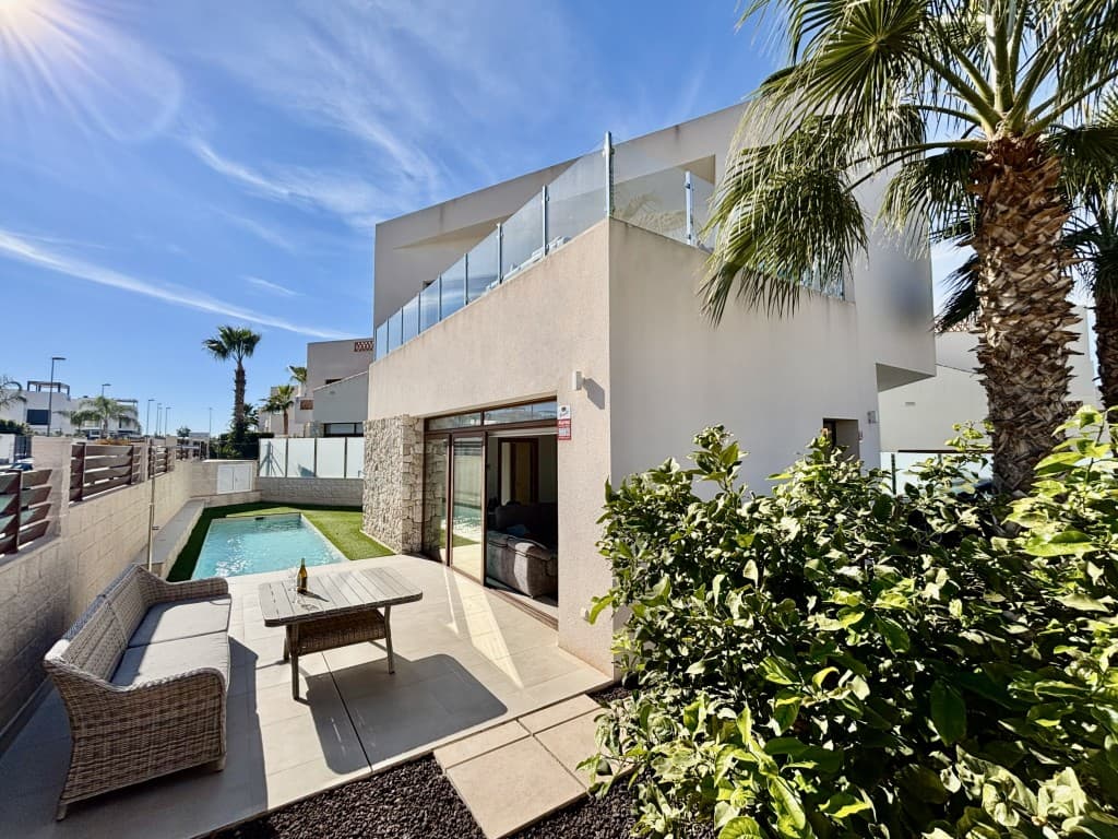 Denne nesten nye, arkitekttegnede frittliggende villaen i den sjarmerende byen Benijófar byr på en sjelden mulighet til å eie en virkelig særegen eiendom. Villaen, opprinnelig bygget som et visningshus og ideelt plassert på en ettertraktet hjørnetomt, kombinerer perfekt moderne arkitektur, eksklusive utførelser og en gjennomtenkt utformet planløsning, noe som gjør den til et av de mest eksepsjonelle hjemmene i området.Fra det øyeblikket du ankommer, imponerer villaen med sin slående moderne design og rene arkitektoniske linjer. Eiendommen er omgitt av vakkert anlagte hager med lite vedlikehold som tilbyr en attraktiv atmosfære året rundt med minimalt vedlikehold. En generøs privat parkeringsplass gir både bekvemmelighet og privatliv, mens den generelle planløsningen forsterker følelsen av rom og komfort.Innvendig ønskes du velkommen til en lys og åpen stue hvor kjøkken, spisestue og stue flyter sømløst sammen. Gulv-til-tak-vinduer flommer inn i interiøret med naturlig lys og gir fantastisk utsikt over terrassen, hagen og det private svømmebassenget. Det elegante, fullt utstyrte kjøkkenet har hvitevarer av høy kvalitet og moderne skap, supplert av et separat vaskerom for ekstra praktisk bruk. Et gjestetoalett er beleilig plassert i denne etasjen.Første etasje har også et romslig dobbelt soverom med eget bad og direkte tilgang til bassengområdet, noe som gjør det ideelt for gjester eller som en luksuriøs hovedsuite i første etasje. Det private svømmebassenget er et sant høydepunkt, og tilbyr et rolig sted å slappe av, underholde gjester eller bare nyte middelhavssolen.Ovenpå finner du ytterligere to romslige dobbeltrom, hvert med eget bad og innredet til en høy standard med komfort og stil i tankene. Begge rommene har god plass og elegante detaljer, noe som skaper fredelige tilfluktssteder for hvile og avslapning. Denne etasjen har også en stor terrasse med åpen utsikt over området rundt – perfekt for morgenkaffe, kveldsdrinker eller for å nyte den rolige atmosfæren.Mer enn bare et hjem, er denne villaen et utstillingsvindu for raffinert design og livsstil. Som et tidligere visningshus inkluderer den skreddersydde funksjoner og førsteklasses materialer som sjelden finnes i standardboliger, med hver detalj nøye vurdert for å maksimere både estetikk og funksjonalitet.Villaen ligger i Benijófar, en av de mest attraktive landsbyene på Costa Blanca, med kort avstand til lokale fasiliteter, inkludert butikker, supermarkeder, restauranter, markeder og naturskjønne turstier. De vakre strendene ligger bare en kort kjøretur unna, og utmerkede veiforbindelser sammen med enkel tilgang til Alicante internasjonale lufthavn gjør reisen uanstrengt.Enten du søker permanent bolig, et stilig feriehus eller en smart investering, tilbyr denne arkitekttegnede villaen enestående verdi i en førsteklasses beliggenhet. Kombinasjonen av unik design, luksuriøse funksjoner og en praktisk planløsning gjør dette til en virkelig eksepsjonell mulighet. Tidlig visning anbefales på det sterkeste, da eiendommer av denne kaliberen sjelden er tilgjengelige.