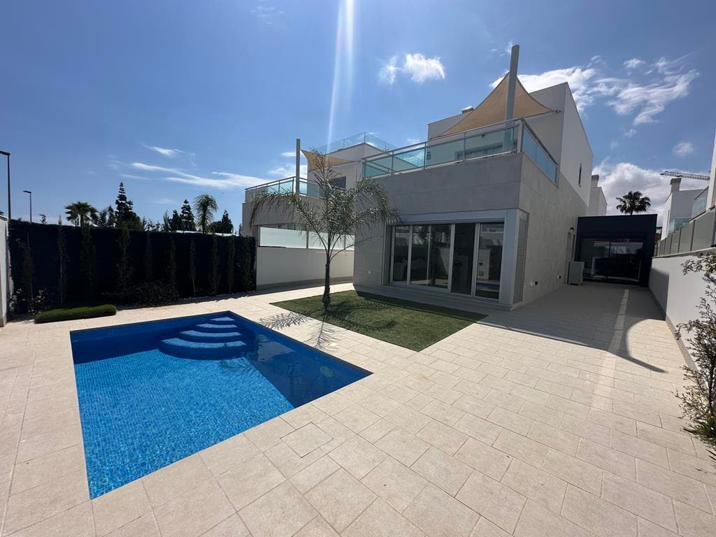 This is a gorgeous detached Norai style villa located next to Serena Golf, Los Alcazares. This well presented villa has it’s own private pool, situated on a large plot with large garden and two solariums. The garage has been remodelled to create a fourth bedroom or office. It is situated close to Serena Golf and walking distance to Los Alcazares old town and you have great views of the Mar Menor from the terrace. It has hot and cold air-con throughout, tv intercom system and off road parking for a couple of cars.The villa is very secure, entered by pin controlled gate and car entry. You enter into the sunny tiled garden with private pool, this space is huge. The open plan kitchen, diner and lounge is very spacious with modern kitchen. The hallway leads to a downstairs cloakroom, and the downstairs double bedroom with ensuite bathroom.Patio doors lead to a private rear terrace with outdoor kitchen / utility area. The garage has been converted to a usable space perfect for a fourth bedroom or an office where you are completely separate from the house. Stairs lead to two further double bedrooms and separate family bathroom. Both bedrooms have built in wardrobes and their own solariums. All windows have electric shutters. This is a gorgeous villa in a prime location. Contact us to arrange a tour of the resort and this wonderful villa.