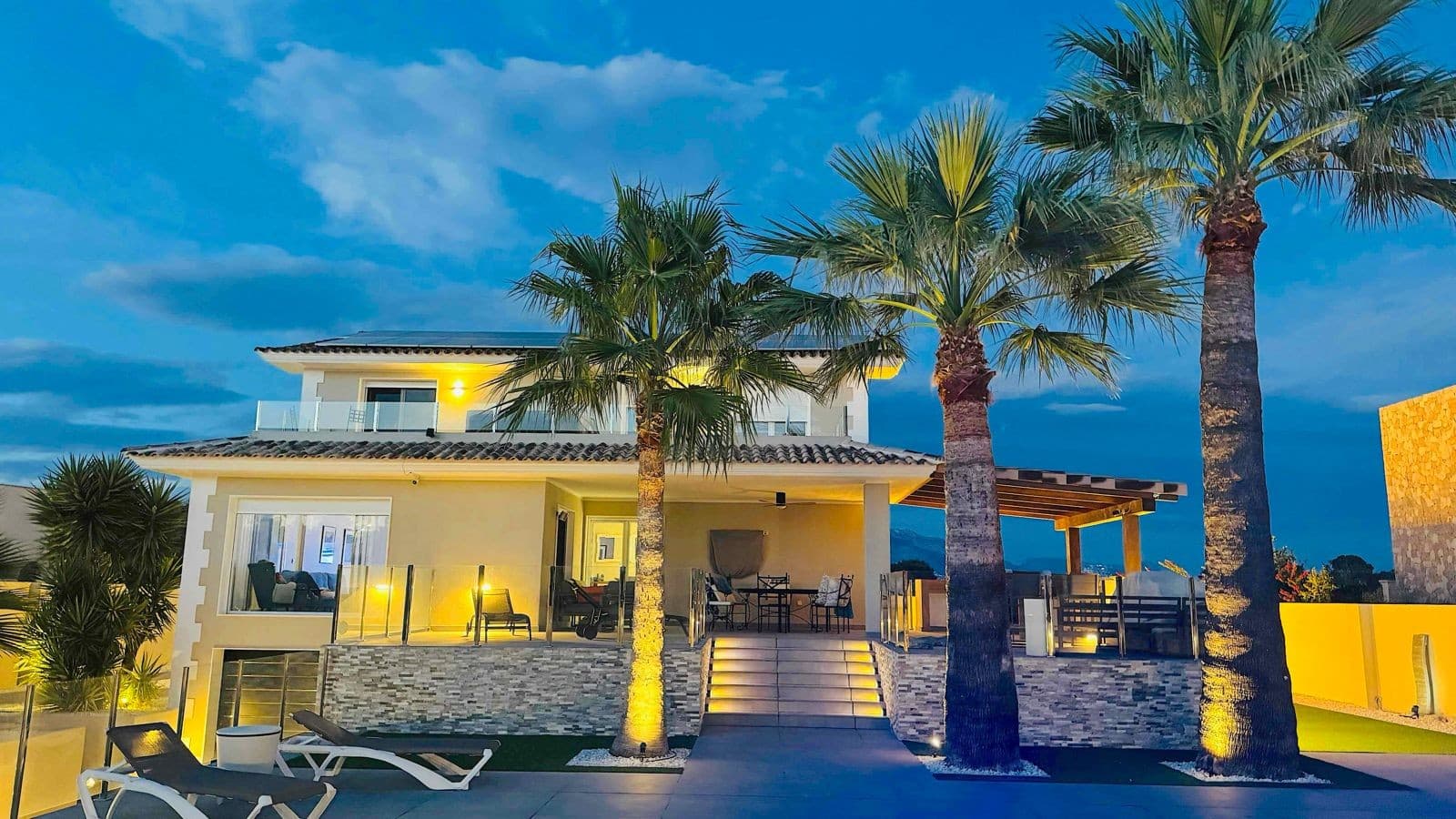 Located in the peaceful and highly sought-after area of Pueblo–Urbanizaciones, Alfaz del Pi, this stunning villa offers the perfect balance of tranquillity and convenience. Just 10 minutes from the beach and 15 minutes from Benidorm, the property enjoys easy access to local amenities, international schools, restaurants, and leisure attractions — all while offering privacy and serenity.Set on a generous 1,250 m² plot with a built area of 347 m², this beautifully renovated villa (2023) has been designed with modern living in mind. Its open-plan layout seamlessly connects the living, dining, and kitchen areas, creating bright, spacious interiors filled with natural light.Interior LayoutThe villa is distributed over two floors plus a basement:Main Floor:A spacious living-dining area with large windows, a high-end open kitchen with central island, one bedroom or home office, and a full bathroom. Integrated LED lighting enhances the atmosphere, creating a warm and welcoming space day and night.Upper Floor:Three generous bedrooms, two with en-suite bathrooms and private terrace access. The master suite is a true highlight, featuring a walk-in wardrobe, elegant en-suite bathroom, and a private terrace with jacuzzi and breathtaking views towards Benidorm’s skyline.Basement:Garage for one car, extensive storage space, and direct internal access to the house.Outdoor LivingDesigned to embrace the Mediterranean lifestyle, the outdoor area is ideal for both relaxation and entertaining. Highlights include:A spectacular 11 x 5 metre swimming pool with night lightingLandscaped gardens and multiple terracesOutdoor dining area and pergola with seatingFully equipped outdoor kitchen with barbecuePétanque court with LED lightingMini putting green for golf enthusiastsEvery detail has been carefully considered to create a private oasis for year-round enjoyment.Comfort & SustainabilityThe villa is equipped with premium features to ensure maximum comfort and efficiency, including underfloor heating, air conditioning, double glazing, electric blinds, filtered drinking water, a security system, and solar panels, offering energy efficiency and partial self-sufficiency.A Move-In Ready Mediterranean HomeThis exceptional villa combines contemporary design, luxury finishes, and functional living spaces in one of the Costa Blanca’s most desirable locations. Whether as a permanent residence or a high-end holiday home, it represents the very best of modern Mediterranean living.Don’t miss the opportunity to visit this outstanding property.Contact us today for more information or to arrange a private viewing.