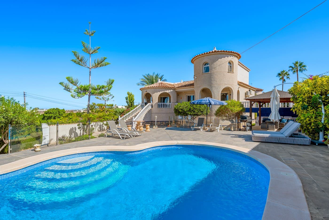 

Enjoy endless sunny days in this magnificent Spanish-style villa, perfectly located in Urb. Lomas De La Juliana, Almoradí, just minutes from the prestigious La Finca Golf Resort.

This impressive 5-bedroom villa offers abundant space for family living and entertaining guests, all in a setting that guarantees privacy and tranquility.

The main house features 3 spacious bedrooms with built-in wardrobes, a fully equipped kitchen, and a generous living room with a beautiful working fireplace and a bright dining area.

With a private entrance, the underbuild apartment provides 2 additional bedrooms, a large living room, and a fully equipped kitchen with ample storage, perfect for hosting guests while ensuring their privacy.

Offering the perfect spot to relax and enjoy yourself after dinner, the garage has been converted into a fun playroom, while a stylish wooden carport comfortably accommodates two cars.

The villa is surrounded by a large, low-maintenance garden, complete with its own putting green to practice your golfing skills.

South-facing and free from direct neighbors, the property offers privacy and stunning views. The spacious terrace is the perfect spot to relax and enjoy spectacular sunsets and lemon tree fields, while the 8x4m swimming pool invites you to cool off on warm days.

Just minutes from the Mediterranean, La Finca Golf is one of the Costa Blanca’s most prestigious resorts. With its championship 18-hole course, luxury hotel, spa, fine dining, and vibrant community, it offers the perfect blend of leisure and elegance. 

This is a rare opportunity,don’t miss your chance! Book a visit today and experience this exceptional home for yourself.