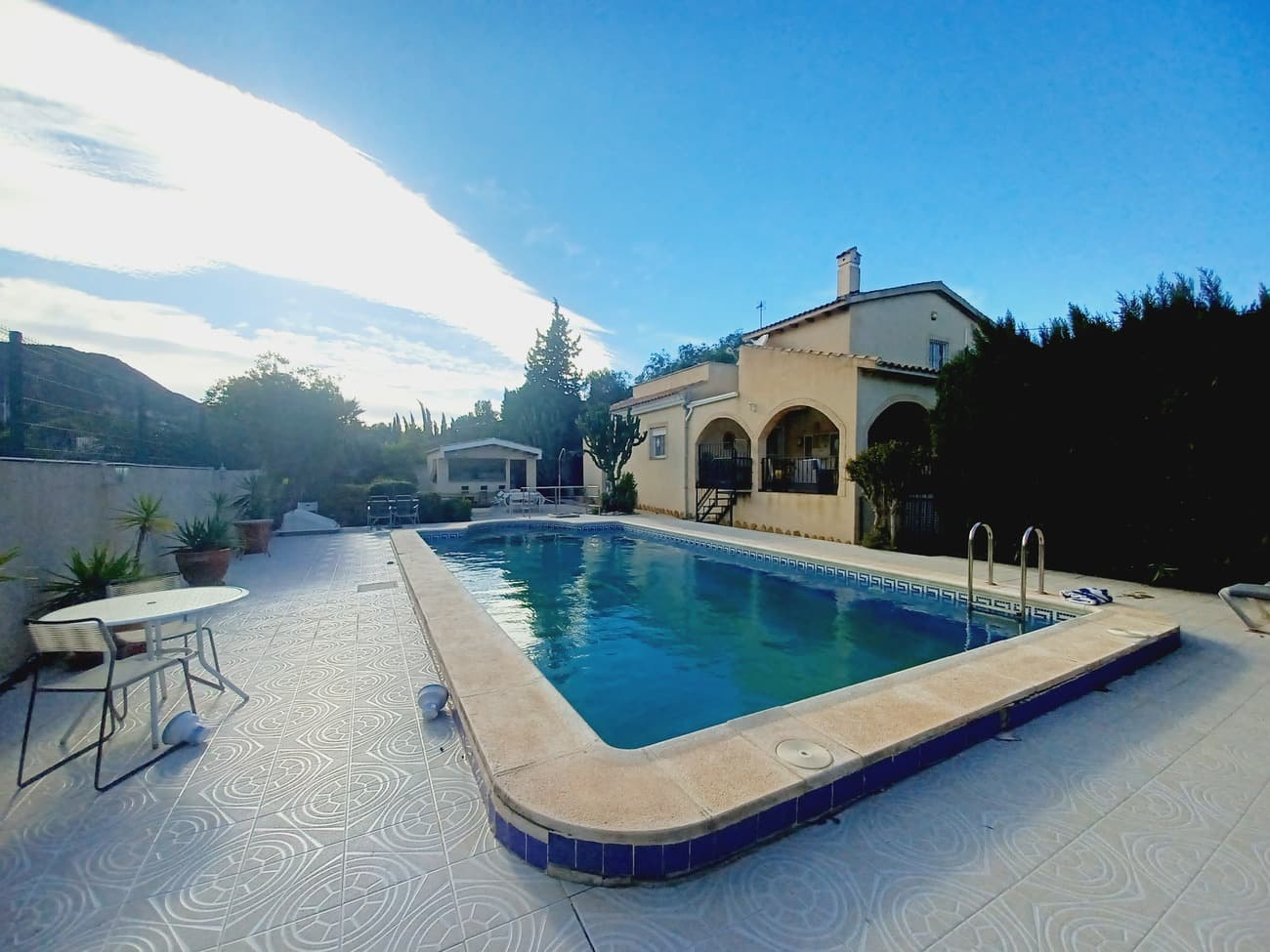 Set in natural mountain park area just 10 minutes to Sucina vllage, this spacious country villa really has it all; with a large plot of 1614m2 this villa has spacious beautiful gardens, a pool, an outdoor kitchen and a very spacious covered terrace to enjoy outdoor living with many seating areas and dining areas. The villa enters into a hallway, with quality tiled flooring throughout and solid wood doors it is well laid out as the hallway leads to the main expansive living & dining room with patio doors to the gardens, a fireplace and furnished tastefully with lounge furniture, glass and metal dining room suite.  The living room leads to a very expansive kitchen with white fitted kitchen, granite worktops, electric oven, hob and extractor, american fridge/freezer and dishwasher with windows and a back door that allows light in from all sides.  The entrance hallway leads to two double bedrooms; the first on the left hand side has a double bed, wardrobes and air conditioning.  The second bedroom on the right hand side is very spacious with fitted wardrobes, 2 single beds as double, bedside cabinets, radiator, air conditioning, wooden drawer unit and window. The downstairs bathroom is large, it comes with a walk in shower, vanity unit and wc.  The living room has a stairwell to the first floor which leads to the master bedroom with en suite bathroom, this is a spacious room with high ceilings, air conditioning, double bed, bedside cabinets and fitted wardrobes with patio doors leading to an en-suite bathroom is spacious with walk-in shower, double sink, wc and bidet.  The upper terrace to enjoy the views of the mountains and overlooking the gardens and pool. The living room patio doors lead to the covered terrace and there are steps leading to the pool area, the pool is a good size with plenty of outdoor terrace areas to enjoy the sunshine.  There is an outdoor kitchen/bar building overlooking the pool, it is a white fitted kitchen, granite worktops and bar, cooker, fridge and microwave oven and wooden shutters overlooking a dining area with wooden table and benches.  The pool area leads with stonework steps to an expansive garden, with various sections it is a well maintained mature garden.  There is a driveway with metal entry gate leading to a covered carport to keep the car protected and in the shade.  The house is surrounded by high brick walls around the whole plot offering privacy and security.  The villa is located in Cañadas de San Pedro, a natural park area of Sierra Espuna mountain range where there are a limited amount of country villas in clusters enjoying beautiful views and good road access by motorway, just 20 minutes to the coast, 20 minutes to the city of Murcia and 20 minutes to the airport of Corvera.  This is a unique and beautiful house offering spacious living, highly recommended for viewing.