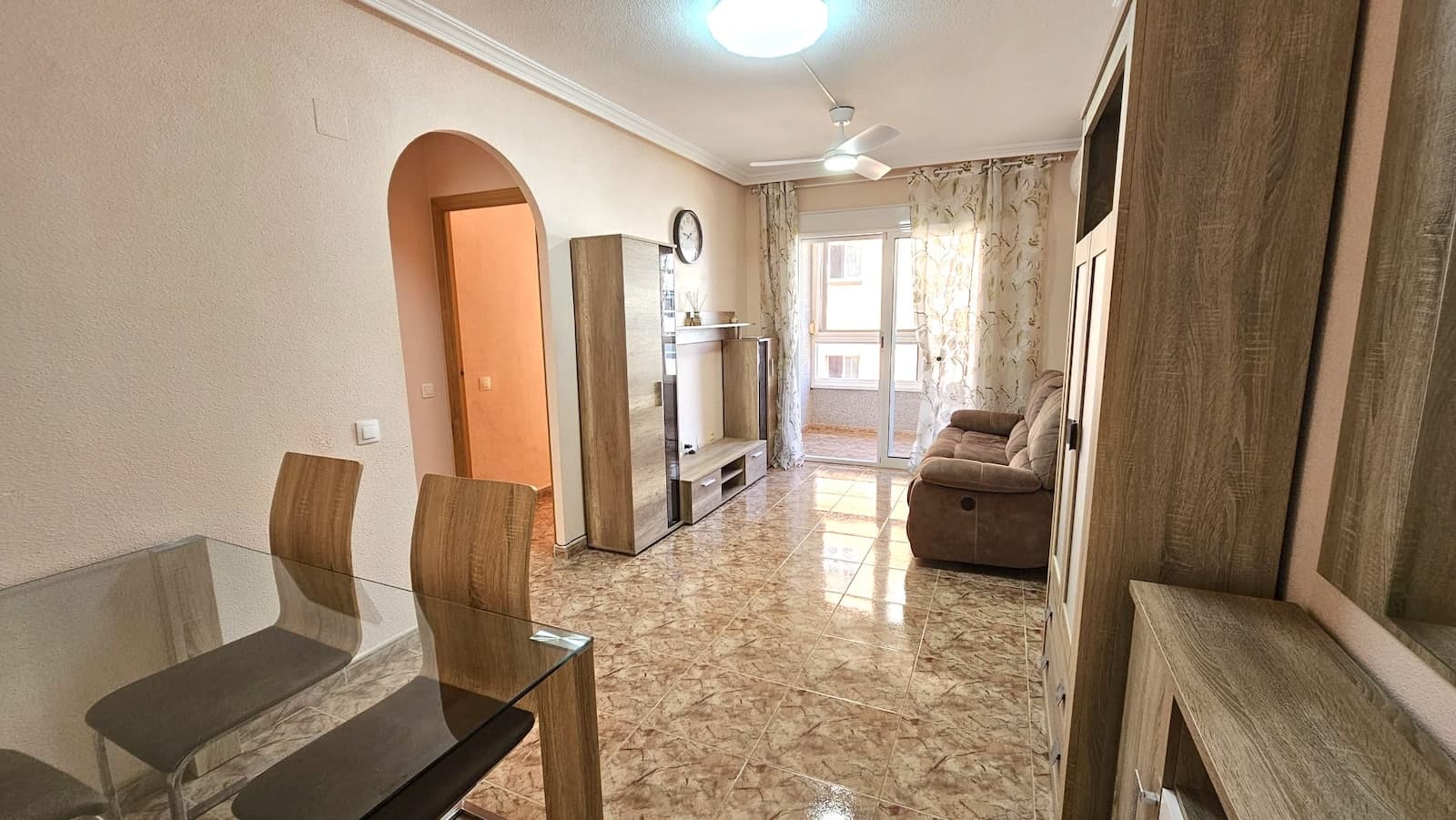 Apartment for sale in Torrevieja, located on Calle San Pascual next to the central Mercadona supermarket. The location is excellent, with shops, central bus station, restaurants, sports facilities, pharmacies, and schools all nearby. Only a 7-minute walk to the beach and the popular promenade at Playa del Cura.The property is on the 3rd floor of a building constructed in 2006. Total area: 65 m². Annual community fee: €295. The balcony is glazed, and all windows are fitted with mosquito screens. The windows face a spacious and quiet courtyard with friendly neighbors. The building is connected to natural gas.The apartment is sold fully furnished with high-quality furniture, including beds with storage systems and premium mattresses. The living room is furnished with a comfortable recliner sofa. Additional features include air conditioning and new ceiling fan-lights operated by remote control.A garage with space for two cars is available for separate purchase. It is located just one building away (3 minutes on foot), on the ground floor, with easy access and automatic doors. The garage is not included in the apartment price.