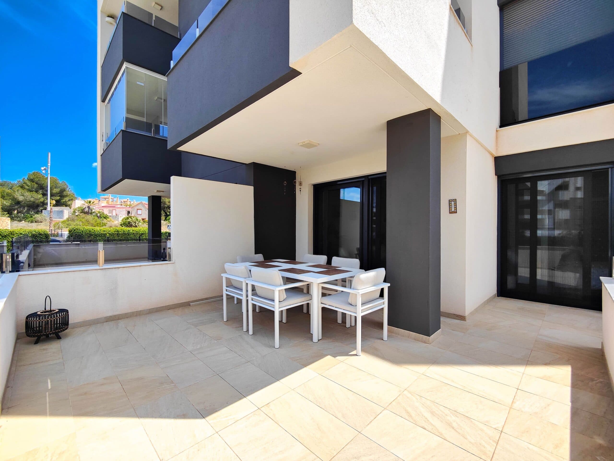 Estupendo apartamento de diseño moderno y de reciente construcción en planta baja y esquina en venta en Res. Amanecer / Sunrise VI - Orihuela Costa.Descubre este elegante y moderno apartamento situado en la planta baja de un prestigioso complejo residencial en Los Altos / La Florida. La propiedad cuenta con una terraza en esquina orientada al suroeste con vistas directas a los preciosos jardines comunitarios y a la piscina.Este luminoso y espacioso apartamento dispone de 2 dormitorios y 2 baños, una moderna zona de estar de concepto abierto y una cocina totalmente equipada con barra americana. La cocina incluye electrodomésticos de alta gama como horno, microondas, frigorífico-congelador, lavavajillas, lavadora y placa vitrocerámica con campana extractora. Para mayor confort, los baños cuentan con calefacción por suelo radiante.Entre sus características adicionales se incluyen ventanas de PVC con persianas eléctricas, aire acondicionado central, y se vende completamente amueblado—listo para entrar a vivir.En el precio se incluye una plaza de aparcamiento subterráneo y un trastero privado.Ubicado en una comunidad cerrada y segura, el complejo ofrece instalaciones excepcionales que incluyen una gran piscina comunitaria, piscina infantil, jardines con palmeras y zonas chill-out, una pista de petanca y un gimnasio con sauna y jacuzzi.Situado en una ubicación ideal, a pocos pasos de un supermercado Aldi y a pocos minutos en coche del reconocido centro comercial Zenia Boulevard y de las hermosas playas de Orihuela Costa.