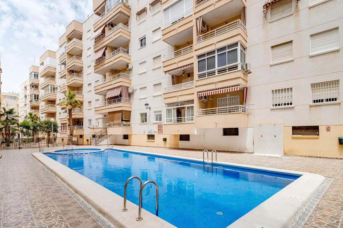 Your Mediterranean retreat awaits you in Torrevieja We present to you this charming ground-floor apartment, located just 700 meters from the emblematic Playa del Cura, one of Torreviejas most vibrant spots. Here you will enjoy more than 300 days of sunshine per year, mild temperatures, and the magic of the Mediterranean just around the corner.The property, built in the year 2000 and in excellent condition, is ready to move into. Its 61 m² are distributed into a cozy living room with an open-plan kitchen, two bright bedrooms, and a modern bathroom. Large windows flood the entire space with natural light, creating a warm and comfortable atmosphere. Key FeaturesGround floor exterior with elevator61 m² built area2 bedrooms and 1 bathroomAir conditioningCommunal swimming poolWell-maintained conditionThe building has a fantastic communal pool, ideal for cooling off on sunny days. Its location is truly privileged within less than five minutes on foot you will find supermarkets, bars, restaurants, parks, shops, pharmacies, a hospital, and the bus station. Everything you need for a comfortable lifestyle is literally at your doorstep.If you wish to explore further, in less than 10 minutes by car you can reach beaches like La Mata or Punta Prima, each with its own charm. And the best part, Alicante International Airport is only 40 minutes away, making this property a perfect option both for year-round living or as an investment for holiday rentals.IBI (Property Tax) €183.78Community Fees 3 annual payments of €156.92Dont miss this unique opportunity in Torrevieja. Call us today and schedule your visit!