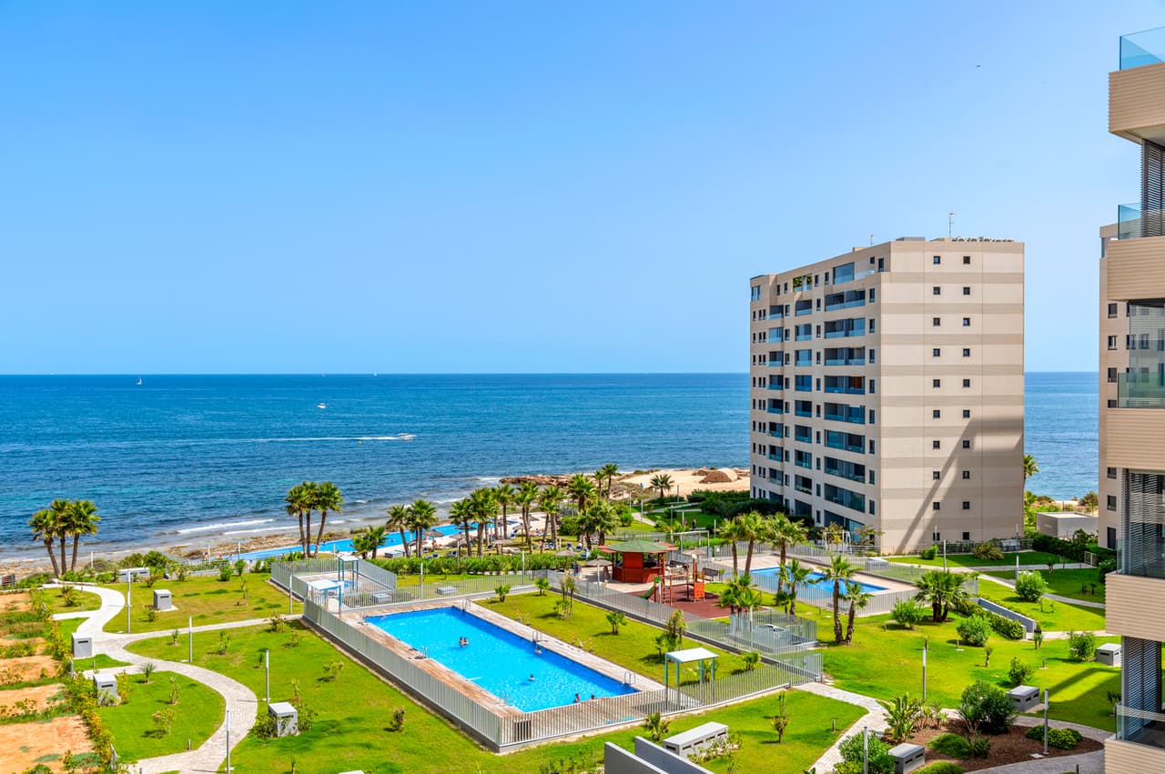 Fantastic exclusive frontline luxury apartment with 2 bedrooms, on the 5th floor, with sea views situated in the popular area of Punta Prima, Alicante.This very modern designed project is set in a very unique location, with large communal garden areas and its unbeatable sea views! The apartment will be sold fully furnished and consist of a spacious and bright living/dining room, a modern fully equipped kitchen, two bedrooms with fitted wardrobes, two bathrooms with underfloor heating, intercom system, air conditioning (hot/cold) throughout the property, an allocated underground parking space and storage room.There is a lovely communal garden with several swimming pools, a heated swimming pool, children’s pool, infinity pool and jacuzzi.