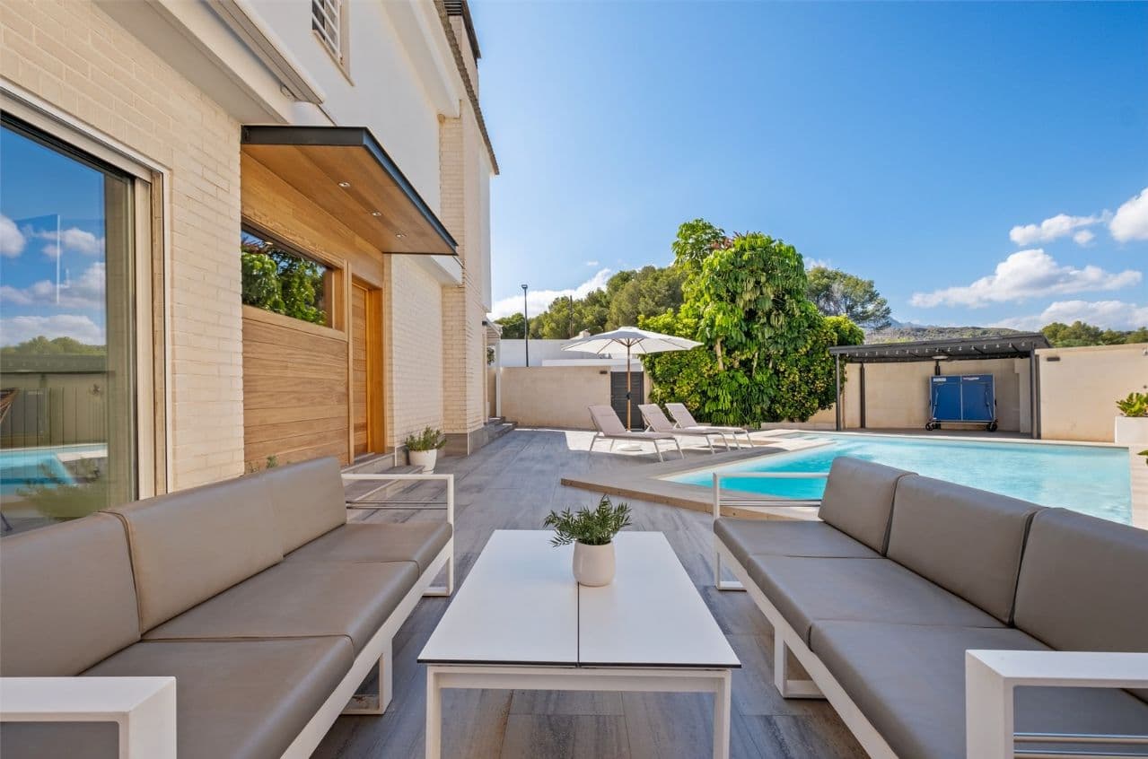 This two-storey semi-detached villa combines modern design and straight lines with a high level of quality and equipment. Everything was refurbished in 2012 to ensure comfortable and efficient living. With 3 bedrooms, 2 bathrooms (one with a large dressing room) and an additional toilet, this home is designed to maximise space and functionality. On the ground floor, in the large hall, there is a spacious living room with direct access to the covered terrace with bioclimatic pergola. The kitchen, completely renovated and equipped with high quality appliances, has a work area and access to the outside, where there is a summer kitchen. On the first floor there are 3 bedrooms and 2 bathrooms. The whole house is equipped with double glazing Climalit, split air conditioning and central heating by radiators. The plot has an elegant seating area next to the seawater pool, ideal for relaxing. There is a water pump in the storage room and in front of the villa there is an additional shed with an open space which is currently used as a gym and is equipped with its own kitchen. Next to it is another storage shed with a toilet. The open area around the barn is designed for covered parking for several cars, the two properties are separated by a privacy wall. 