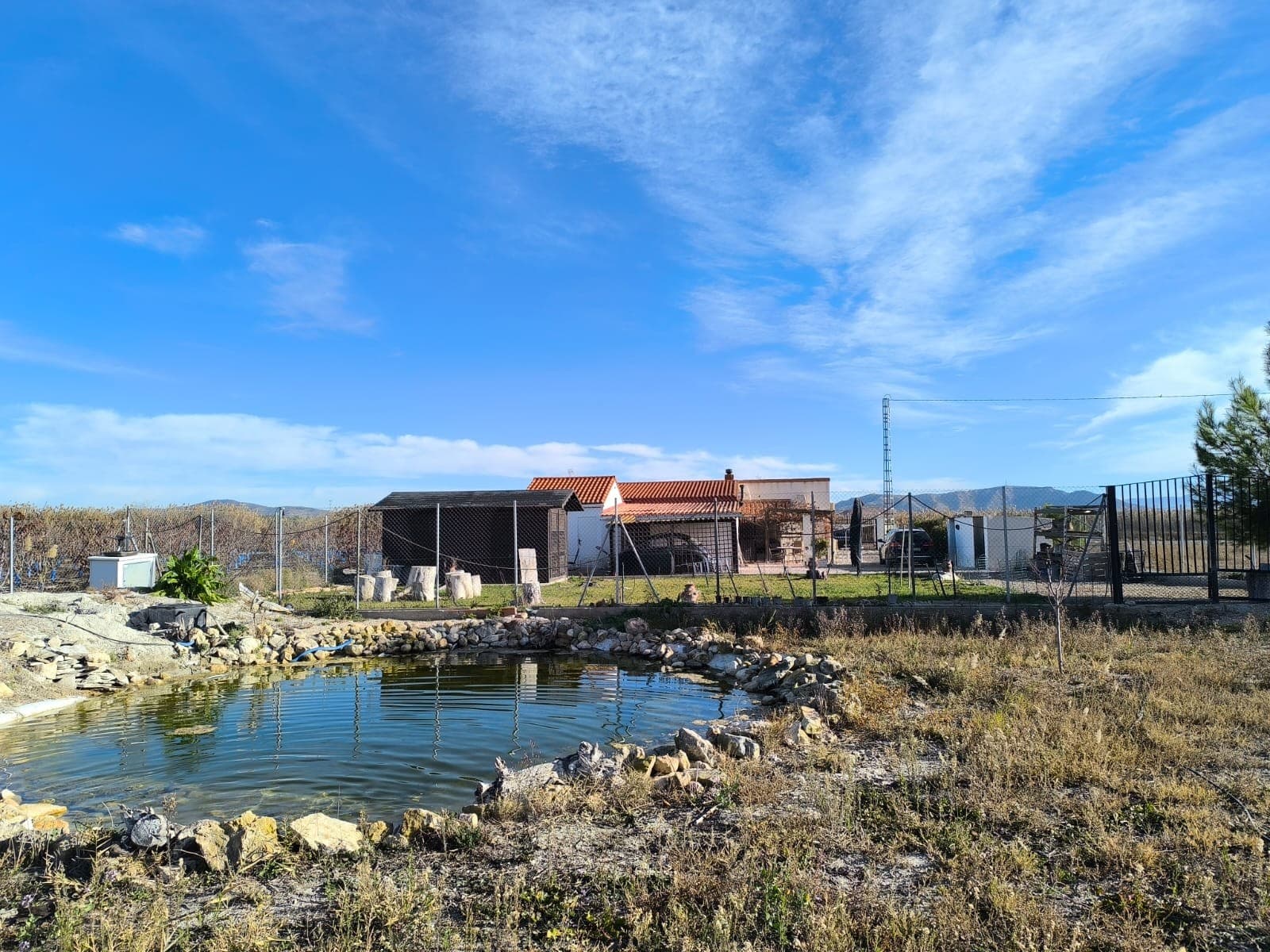 Spacious 5-Bedroom Villa with Guest Studio, Pool & Jacuzzi – Villena, AlicanteThis well-maintained villa near Villena offers generous indoor and outdoor living on an 8,000 m² fully fenced plot with beautiful gardens, fruit trees and an olive orchard. With 210 m² built, the property includes a 4-bedroom main house and a separate guest studio, making it ideal for families, guests or those seeking extra space for work or leisure.The main house is set on one level and features 4 bedrooms and 2 bathrooms, a large living room with fireplace, and a spacious office area with an additional small room—perfect for remote work, hobbies or storage. The home also includes a covered outdoor terrace fitted with fly screens, providing a comfortable seating and dining area to enjoy the views year-round. There is also a car port behind the house for 1 car.Outside, the property offers excellent facilities, including a 5x7 m swimming pool, a 6-person jacuzzi, several storage outbuildings, a tool shed and a wooden storage cabin surrounded by its own fenced garden with real grass and fruit trees. Behind the house is a detached guest studio with its own entrance, bedroom and ensuite bathroom—ideal for visitors or extended family.The land is fully irrigated automatically and divided into two sections:  Front orchard with 35 mature olive trees Back garden area with apple, cherry, pear, fig and other fruit trees, plus a large pond The fencing and electrical installation have been recently updated, providing peace of mind and easy maintenance.About the area: The villa is located just a short drive from Villena, a historic inland town known for its medieval castle, vibrant cultural life and excellent local services. Villena offers supermarkets, shops, restaurants, schools, a high-speed train station and quick access to Alicante, which is less than an hour away. Surrounded by vineyards, mountains and open countryside, the area is perfect for enjoying nature while staying close to all daily amenities.A spacious, versatile country home in a peaceful setting with stunning mountain views — ideal as a family residence, a countryside retreat or a property with guest accommodation ready to use from day one. We have a large portfolio of properties in the Costa Blanca and Costa Calida areas, specialising in country properties, villas, fincas, building plots and design and build options in the Alicante and Murcia regions with a particular emphasis on Elda, Monovar, Pinoso, Sax, Villena, Aspe, Fortuna, Albacete and many more surrounding areas. We have been established since 2004 and have decades of experience between the team which we bring to bear to help you find and secure your new dream home. We help you every step of the way to make sure your purchase in Spain is safe and hassle free. We are not here to sell you a property, we are here to help you realise your dream and find what is right for you. With us you are in the safest hands. Contact us now to have a no obligation chat about how you too can realise your dreams.