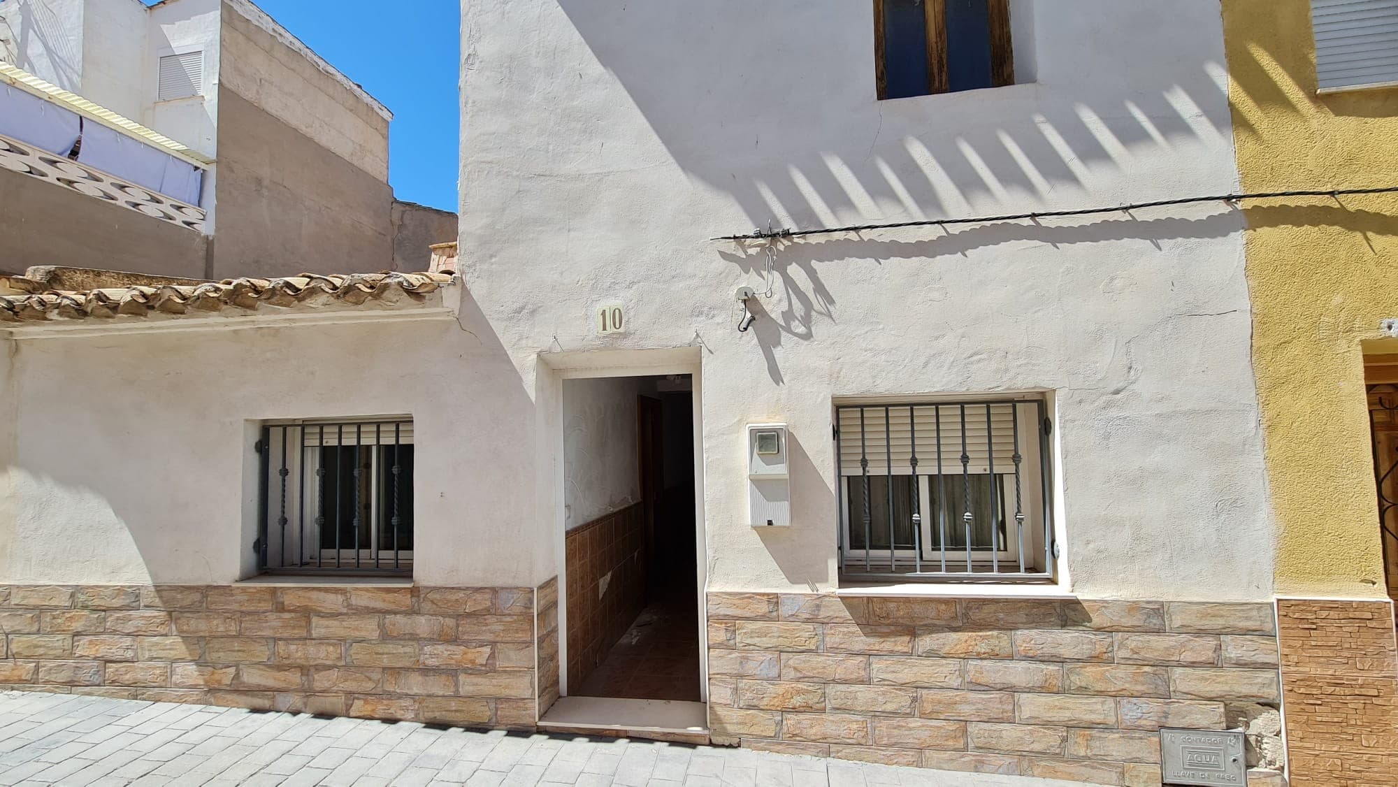 Esta casa adosada de 4 dormitorios y 1 baño en Salinas, Alicante, ofrece un espacio amplio con potencial para personalización. La propiedad cuenta con un pequeño patio de lavandería y se entrega amueblada, incluyendo electrodomésticos. El aire acondicionado garantiza el confort durante todo el año. Aunque actualmente no hay suministro de electricidad ni agua, están disponibles. La planta superior está vacía, lo que ofrece una excelente oportunidad para crear una suite principal. La casa adosada incluye un amplio garaje y, a pesar de algunos daños por agua, se encuentra en buen estado general. Si se paga el precio total, los vendedores reconectarán el agua y la electricidad por su cuenta. Esta casa adosada, convenientemente ubicada a poca distancia de todos los servicios, es perfecta para aquellos que buscan personalizar su nuevo hogar mientras disfrutan de las ventajas de una ubicación céntrica. Contamos con una amplia cartera de propiedades en la Costa Blanca y la Costa Cálida, especializadas en fincas rurales, villas, terrenos edificables y opciones de diseño y construcción en Alicante y Murcia, con especial énfasis en Elda, Monóvar, Pinoso, Sax, Villena, Aspe, Fortuna, Albacete y alrededores. Fundada en 2004, nuestra empresa cuenta con décadas de experiencia que ponemos a su disposición para ayudarle a encontrar y adquirir la casa de sus sueños. Le acompañamos en cada paso del proceso para garantizar una compra segura y sin complicaciones en España. Nuestro objetivo no es venderle una propiedad, sino ayudarle a hacer realidad su sueño y encontrar la opción perfecta para usted. Con nosotros, su compra está en las mejores manos. Contáctenos hoy mismo para una charla sin compromiso sobre cómo usted también puede hacer realidad sus sueños.