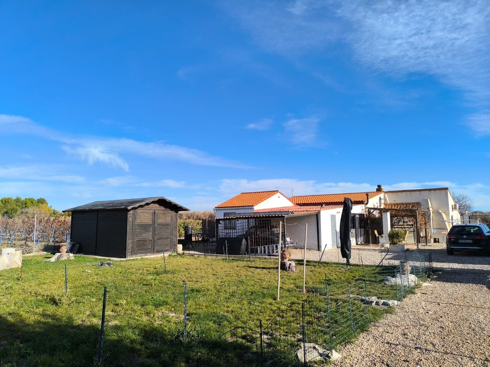 Espaciosa villa de 5 dormitorios con estudio de invitados, piscina y jacuzzi – Villena, Alicante Esta villa bien cuidada cerca de Villena ofrece amplios espacios interiores y exteriores en una parcela de 8.000 m² totalmente vallada con hermosos jardines, árboles frutales y un olivar. Con 210 m² construidos , la propiedad incluye una casa principal de 4 dormitorios y un estudio independiente para invitados, lo que la convierte en ideal para familias, invitados o quienes buscan espacio adicional para trabajar o disfrutar del tiempo libre. La casa principal es de una sola planta y cuenta con 4 dormitorios y 2 baños , un amplio salón con chimenea y una espaciosa oficina con una pequeña habitación adicional, ideal para teletrabajar, disfrutar de aficiones o guardar cosas. La casa también incluye una terraza exterior cubierta con mosquiteras, que ofrece un cómodo espacio para sentarse y comer y disfrutar de las vistas durante todo el año. También hay una cochera detrás de la casa para un coche. En el exterior, la propiedad ofrece excelentes instalaciones, incluyendo una piscina de 5x7 m , un jacuzzi para 6 personas , varias dependencias de almacenamiento, un cobertizo para herramientas y una cabaña de madera rodeada de su propio jardín vallado con césped natural y árboles frutales. Detrás de la casa hay un estudio independiente para invitados con entrada independiente, dormitorio y baño privado, ideal para visitas o familias numerosas. El terreno está totalmente regado de forma automática y dividido en dos secciones: Huerto delantero con 35 olivos maduros Zona de jardín trasero con manzanos, cerezos, perales, higueras y otros árboles frutales, además de un gran estanque. La cerca y la instalación eléctrica se han actualizado recientemente, lo que proporciona tranquilidad y un fácil mantenimiento. Sobre la zona: La villa se encuentra a poca distancia en coche de Villena , un histórico pueblo del interior conocido por su castillo medieval, su vibrante vida cultural y sus excelentes servicios locales. Villena ofrece supermercados, tiendas, restaurantes, colegios, una estación de tren de alta velocidad y un rápido acceso a Alicante, que está a menos de una hora. Rodeada de viñedos, montañas y campo abierto, la zona es perfecta para disfrutar de la naturaleza y estar cerca de todos los servicios diarios. Una casa de campo espaciosa y versátil en un entorno tranquilo con impresionantes vistas a la montaña, ideal como residencia familiar, un refugio en el campo o una propiedad con alojamiento para invitados lista para usar desde el primer día. Disponemos de una amplia cartera de propiedades en la Costa Blanca y la Costa Cálida, especializándonos en fincas rústicas, villas, fincas, terrenos edificables y opciones de diseño y construcción en las regiones de Alicante y Murcia, con especial énfasis en Elda, Monóvar, Pinoso, Sax, Villena, Aspe, Fortuna, Albacete y muchas otras zonas de los alrededores. Llevamos establecidos desde 2004 y nuestro equipo cuenta con décadas de experiencia para ayudarle a encontrar y asegurar la casa de sus sueños. Le acompañamos en cada paso del proceso para garantizar que su compra en España sea segura y sin complicaciones. No estamos aquí para venderle una propiedad, sino para ayudarle a hacer realidad su sueño y encontrar la propiedad perfecta para usted. Con nosotros, está en las mejores manos. Contáctenos ahora para hablar sin compromiso sobre cómo usted también puede hacer realidad sus sueños.