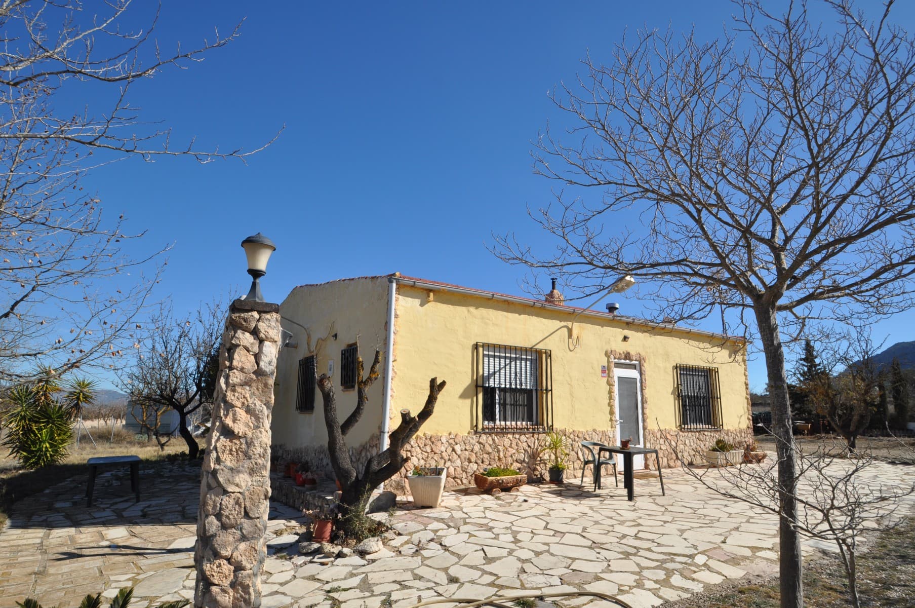 Ubicada a solo unos minutos de la encantadora ciudad de Salinas, Alicante, esta propiedad ofrece un estilo de vida rural tranquilo con comodidades modernas. Ubicada en una parcela vallada de 9.320 m² con almendros, esta casa ofrece espacio, privacidad y fácil acceso a través de un camino completamente pavimentado hasta la entrada. La casa principal tiene 100 m² y está bien distribuida, mientras que una unidad de invitados independiente de 55 m², parcialmente móvil y parcialmente construida, agrega espacio habitable adicional. La propiedad incluye un pequeño huerto con lechuga, tomates y otros productos frescos, así como una zona vallada para gallinas, lo que la hace ideal para quienes buscan adoptar un estilo de vida más autosuficiente. Disfrute de los beneficios de vivir en el campo sin estar aislado. Esta casa ofrece independencia y, al mismo tiempo, está cerca de los servicios locales. Una gran oportunidad para quienes buscan un retiro tranquilo en el campo de Alicante. Si te ha gustado esta propiedad no dudes en contactarnos para organizar una visita, estaremos encantados de ayudarte!