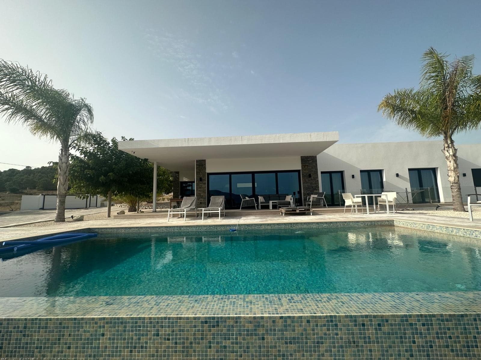 Esta villa sobre plano ofrece un diseño moderno con una superficie construida de 148 m², tres dormitorios, dos baños y una luminosa cocina abierta con salón. La distribución es funcional y está diseñada para una vida cómoda durante todo el año. El precio incluye piscina privada y la casa se puede personalizar según sus necesidades. La villa se construirá en una parcela de 10.000 m², que no está incluida en el precio base. Ofrecemos una amplia selección de más de 150 parcelas legales en diversas zonas rurales. Los precios de las parcelas y el coste final pueden variar según la ubicación y las características elegidas. Este tipo de obra nueva es ideal para quienes buscan espacio, privacidad y flexibilidad, a la vez que se encuentran cerca de pueblos como Pinoso, La Romana o Monóvar. Estas zonas son conocidas por sus paisajes, viñedos y su encanto tradicional español, a la vez que se mantienen cerca de la costa y del aeropuerto de Alicante. Perfectas para vivir a tiempo completo o como refugio vacacional. Disponemos de una amplia cartera de propiedades en la Costa Blanca y la Costa Cálida, especializándonos en fincas rústicas, villas, fincas, terrenos edificables y opciones de diseño y construcción en las regiones de Alicante y Murcia, con especial énfasis en Elda, Monóvar, Pinoso, Sax, Villena, Aspe, Fortuna, Albacete y muchas otras zonas de los alrededores. Llevamos establecidos desde 2004 y nuestro equipo cuenta con décadas de experiencia para ayudarle a encontrar y asegurar la casa de sus sueños. Le acompañamos en cada paso del proceso para garantizar que su compra en España sea segura y sin complicaciones. No estamos aquí para venderle una propiedad, sino para ayudarle a hacer realidad su sueño y encontrar la propiedad perfecta para usted. Con nosotros, está en las mejores manos. Contáctenos ahora para hablar sin compromiso sobre cómo usted también puede hacer realidad sus sueños.