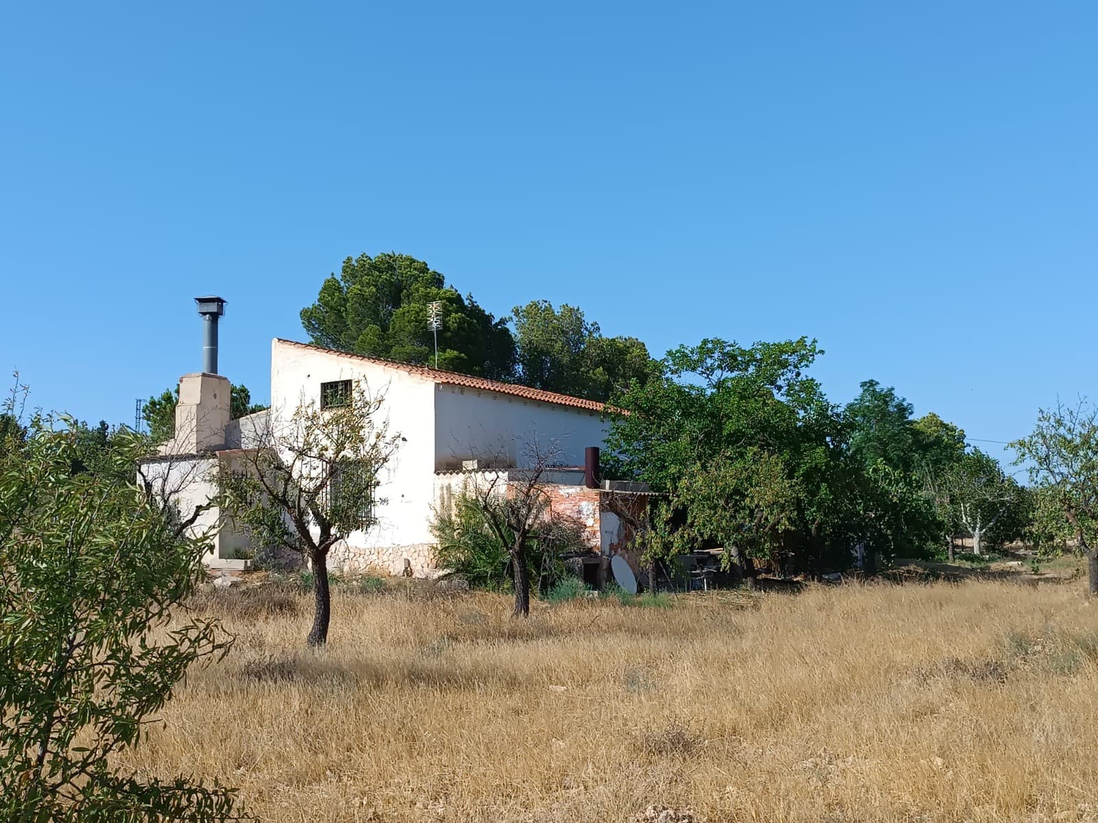 ¿Buscas una casa nueva a un precio asequible en un entorno rural tranquilo? Te presentamos una impresionante casa de campo con una amplia parcela y piscina, a 7 km de Yecla, en un entorno natural y tranquilo. Si buscas comodidad, privacidad y vistas impresionantes, y buscas una casa en buen estado y lista para entrar a vivir, esta es la propiedad perfecta. Con 222 m² construidos, 125 m² se dedican a la vivienda, con 3 dormitorios, un baño, un acogedor salón con chimenea y una cocina. El resto de la construcción consta de garaje, trastero y un porche cubierto. La casa se vende completamente amueblada y cuenta con luz, agua de red y agua de riego. Lo más destacado de esta propiedad es su espaciosa y funcional piscina de 108.000 l, ubicada justo al lado del porche cubierto. La casa se asienta sobre una amplia parcela de 18.000 m², lo que ofrece privacidad y diversas posibilidades para ampliaciones, dependencias o explotaciones agrícolas. La parcela cuenta con varios árboles frutales para autoconsumo, y la mayor parte está dedicada a un huerto de almendros. Gracias a su tamaño y ubicación, la propiedad es ideal para los amantes de los caballos. ¡No lo dudes y contacta con nosotros para concertar una visita! Sobre la zona: Yecla es famosa por su producción vinícola, sus monumentos históricos y su vibrante cultura local. Los paisajes naturales que la rodean ofrecen la oportunidad de practicar actividades al aire libre, mientras que el pueblo ofrece todos los servicios necesarios, como escuelas, tiendas y restaurantes. Esta propiedad combina la tranquilidad de la vida rural con fácil acceso a servicios modernos. Sobre nosotros: Contamos con una amplia cartera de propiedades en la Costa Blanca y la Costa Cálida, especializándonos en fincas, villas, fincas, terrenos edificables y opciones de diseño y construcción en las regiones de Alicante y Murcia, con especial énfasis en Elda, Monóvar, Pinoso, Sax, Villena, Aspe, Fortuna, Albacete y muchas otras zonas de los alrededores. Llevamos establecidos desde 2004 y nuestro equipo cuenta con décadas de experiencia para ayudarle a encontrar y asegurar la casa de sus sueños. Le acompañamos en cada paso del proceso para garantizar que su compra en España sea segura y sin complicaciones. No estamos aquí para venderle una propiedad, sino para ayudarle a hacer realidad su sueño y encontrar la propiedad perfecta para usted. Con nosotros, está en las mejores manos. Contáctenos ahora para hablar sin compromiso sobre cómo usted también puede hacer realidad sus sueños.