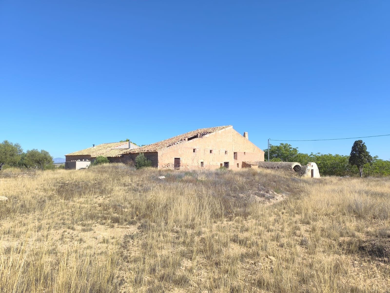 ¡Una oportunidad única de poseer y recrear un trocito de la historia española! Esta propiedad única, que antiguamente fue una bodega y una casa de campo, cuenta con 600 m² de superficie construida con un enorme potencial para una casa extraordinaria o un negocio en el corazón de la región vinícola de Vinolapo. La casa, completamente vallada, es adosada y comparte acceso con la propiedad vecina (no está habitada). Situada cerca del pueblo de Raspay, a poca distancia en coche de Pinoso, ofrece impresionantes vistas de los valles y montañas circundantes. Una combinación perfecta de tranquilidad y fácil acceso, a solo 50 minutos de las playas y del aeropuerto de Alicante. Las posibilidades para la planta baja son infinitas. Muchos de los elementos originales aún se conservan: el lagar de aceitunas, dos fosas de vino originales, fácilmente reconvertidas en almacén, y un lagar de roble y una prensa de metal originales. También hay un enorme depósito de agua antiguo con un precioso arco, que podría transformarse en un fabuloso comedor, un singular auditorio de música con la acústica del techo abovedado o incluso en una piscina cubierta o jacuzzi. La planta superior cuenta con techos altos con vigas y curvas, y podría transformarse fácilmente en una fantástica sala de estar. La propiedad necesita una reforma integral. Vea el vídeo del recorrido para hacerse una idea de la cantidad de trabajo necesario. Esta propiedad tiene el potencial de convertirse en un magnífico restaurante o un alojamiento y desayuno único, o simplemente restaurarse a su antigua gloria utilizando las características originales que aún se conservan en la propiedad. Sobre la zona: Raspay, un pueblo típico español, pero acogedor para expatriados, se encuentra a 5 minutos en coche de Pinoso y a 20 minutos de Yecla y todos sus servicios. El paraje natural protegido Sierra del Carche ofrece amplias oportunidades para practicar senderismo y un potencial que se está descubriendo poco a poco para el turismo rural. Rodeado de pintorescos viñedos y ondulantes colinas, Pinoso es reconocido por su calidad de vida, con excelentes servicios locales, colegios y fácil acceso a las vibrantes ciudades de Alicante y Elche, así como a las hermosas playas mediterráneas. Tanto si busca un tranquilo refugio rural como una comunidad familiar, Pinoso es el lugar ideal para invertir en propiedades, ya que combina una vida tranquila con un gran potencial de crecimiento. Sobre nosotros : Disponemos de una amplia cartera de propiedades en la Costa Blanca y la Costa Cálida, especializándonos en fincas, villas, fincas, terrenos edificables y opciones de diseño y construcción en las regiones de Alicante y Murcia, con especial énfasis en Elda, Monóvar, Pinoso, Sax, Villena, Aspe, Fortuna, Albacete y muchas otras zonas de los alrededores. Llevamos establecidos desde 2004 y nuestro equipo cuenta con décadas de experiencia para ayudarle a encontrar y asegurar la casa de sus sueños. Le acompañamos en cada paso del proceso para garantizar que su compra en España sea segura y sin complicaciones. No estamos aquí para venderle una propiedad, sino para ayudarle a hacer realidad su sueño y encontrar la propiedad perfecta para usted. Con nosotros, está en las mejores manos. Contáctenos ahora para charlar sin compromiso sobre cómo usted también puede hacer realidad sus sueños.