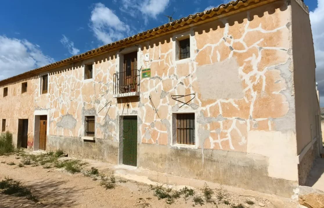 Esta espectacular casa tradicional adosada ha sido restaurada con maestría utilizando materiales y artesanía de primera calidad, combinando el encanto rústico con el confort moderno. Con 211 m² de superficie habitable en dos plantas y un total de 338 m² construidos, incluyendo un espacioso garaje de 110 m², la propiedad ofrece: 6 dormitorios, 3 baños Una luminosa sala de estar con chimenea. Una cocina totalmente equipada y suelos de gres en toda la vivienda. Características tradicionales restauradas con sensibilidad Terraza en la azotea La casa está conectada a la red de riego y cuenta con un sistema solar fotovoltaico que cubre plenamente las necesidades energéticas de la propiedad. La renovación está a punto de finalizar, con cada detalle cuidadosamente seleccionado, incluyendo una decoración tradicional artesanal que realza su carácter único. Ubicada a solo 10 km de Yecla, con cómodo acceso, esta es una oportunidad única de poseer una casa bellamente restaurada en un entorno rural tranquilo. Sobre la zona: Yecla es un encantador e histórico pueblo de aproximadamente 35.000 habitantes, situado en la Región de Murcia. Es famoso por sus vinos galardonados, sus monumentos históricos y su vibrante cultura local. Los paisajes naturales que lo rodean, con pintorescas montañas, viñedos y almendros, ofrecen la oportunidad de practicar actividades al aire libre, mientras que el pueblo cuenta con todos los servicios necesarios, como hospital, escuelas, tiendas, restaurantes y otros. Con una comunidad local amable, mercados animados, excelente gastronomía y fácil acceso a la naturaleza, Yecla es un lugar ideal para quienes buscan el auténtico estilo de vida español, a solo una hora de la costa y del aeropuerto de Alicante. Sobre nosotros: Disponemos de una amplia cartera de propiedades en la Costa Blanca y la Costa Cálida, especializándonos en fincas, villas, fincas, terrenos edificables y opciones de diseño y construcción en las regiones de Alicante y Murcia, con especial énfasis en Elda, Monóvar, Pinoso, Sax, Villena, Aspe, Fortuna, Albacete y muchas otras zonas de los alrededores. Llevamos establecidos desde 2004 y nuestro equipo cuenta con décadas de experiencia para ayudarle a encontrar y asegurar la casa de sus sueños. Le acompañamos en cada paso del proceso para garantizar que su compra en España sea segura y sin complicaciones. No estamos aquí para venderle una propiedad, sino para ayudarle a hacer realidad su sueño y encontrar la propiedad perfecta para usted. Con nosotros, está en las mejores manos. Contáctenos ahora para hablar sin compromiso sobre cómo usted también puede hacer realidad sus sueños.